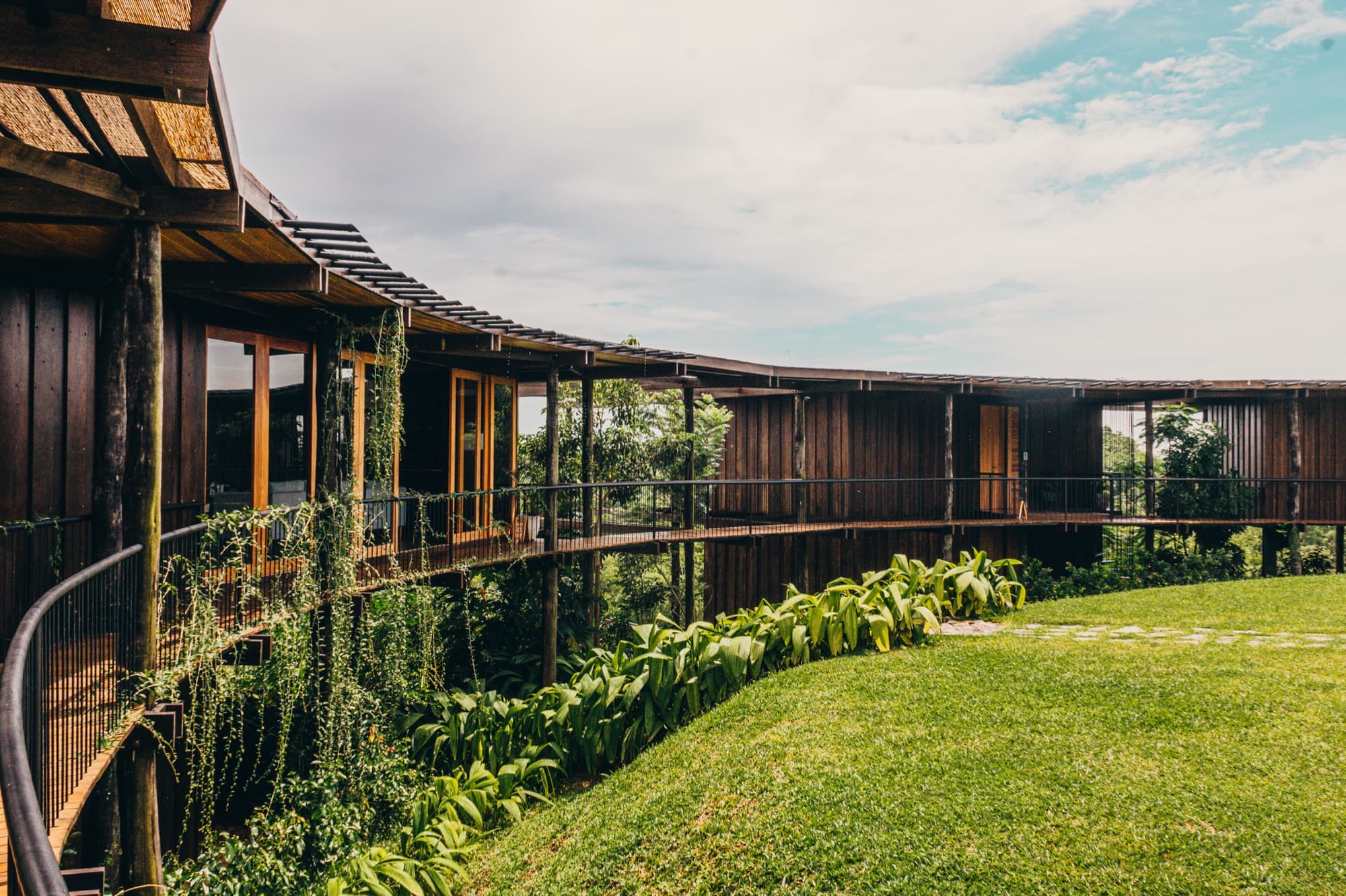 Curved timber facade and walkway of the roundhouse above a garden lawn