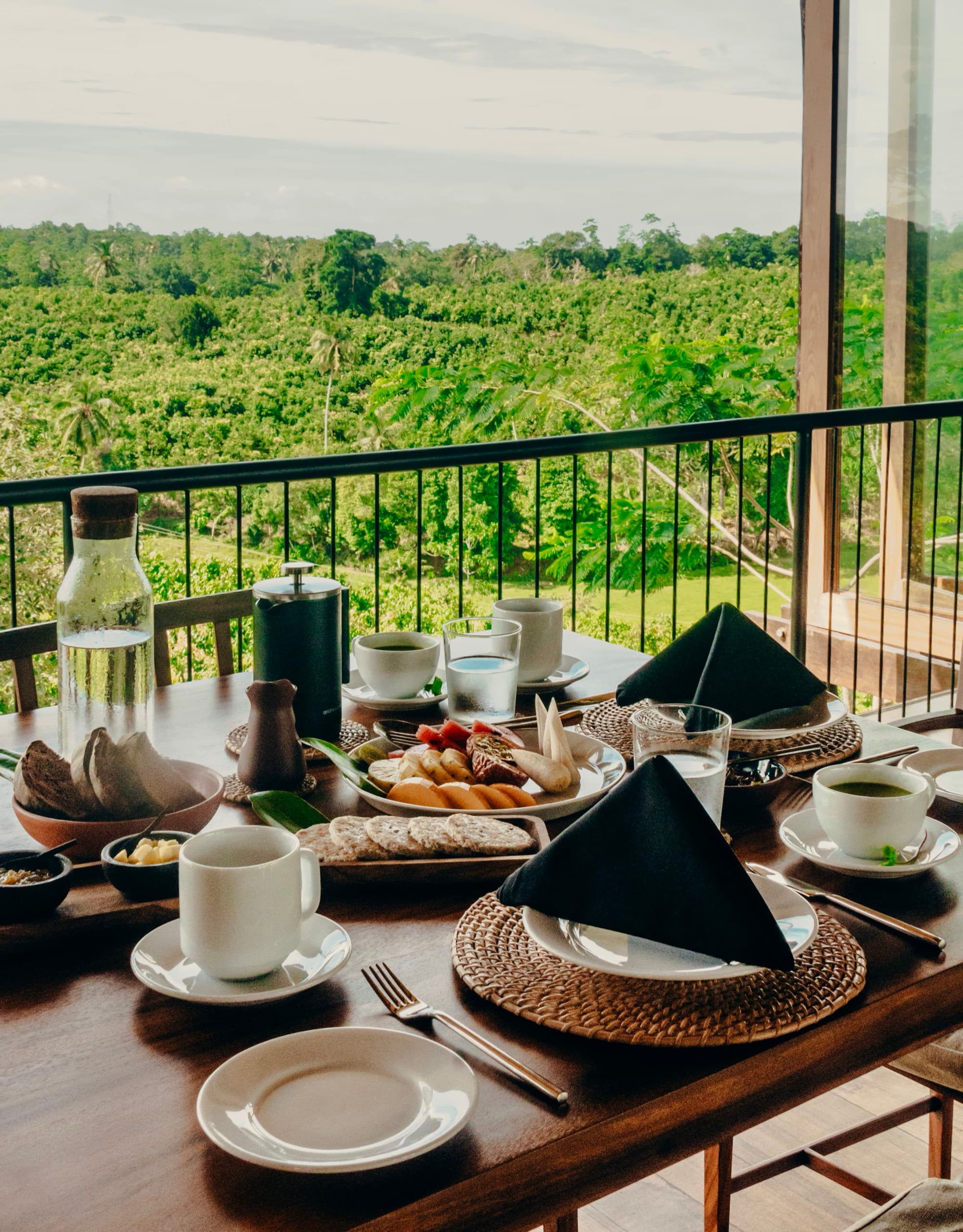 Breakfast spread on a balcony table above a canopy of palms