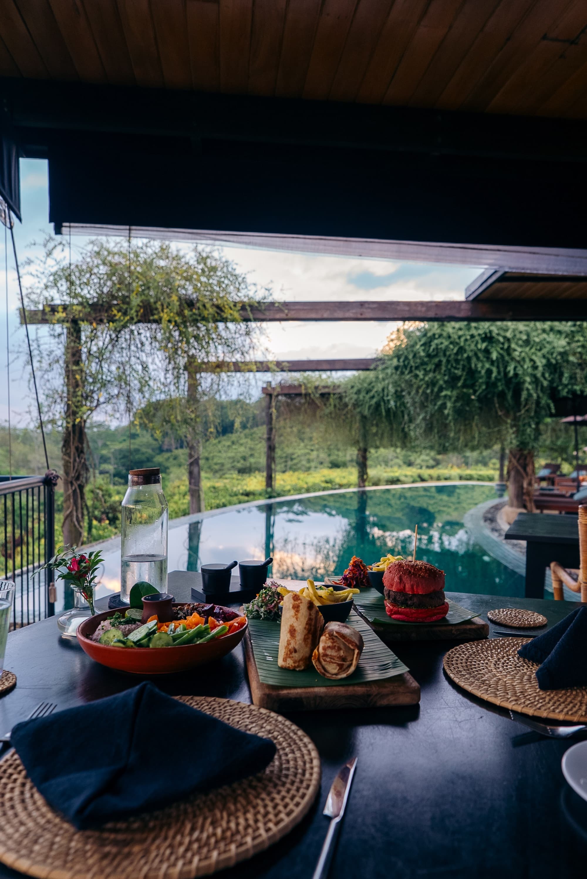 Colourful lunch dishes on a table with the infinity pool and jungle beyond
