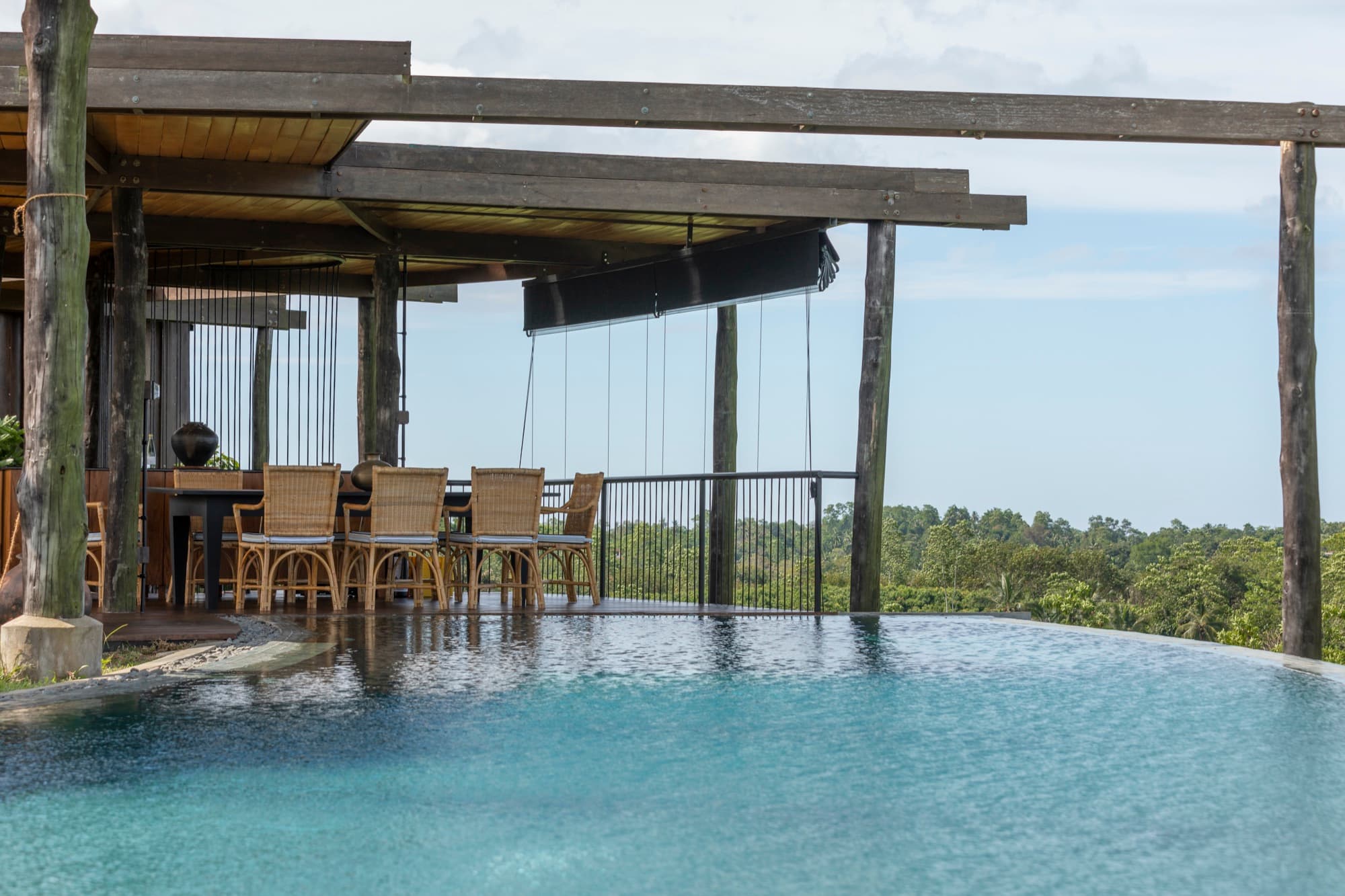 Infinity pool beside a timber pergola dining terrace overlooking the jungle