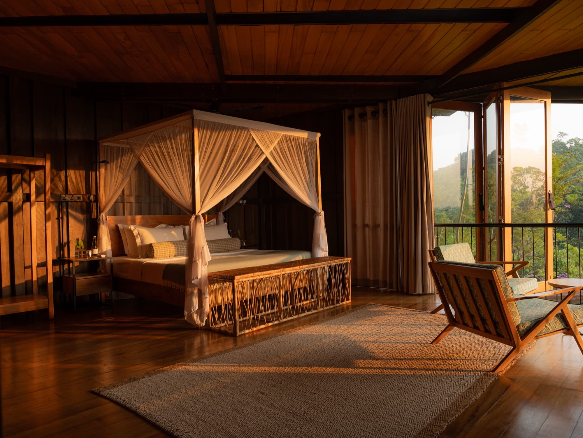 King room with a canopy bed and timber ceiling bathed in warm sunset light