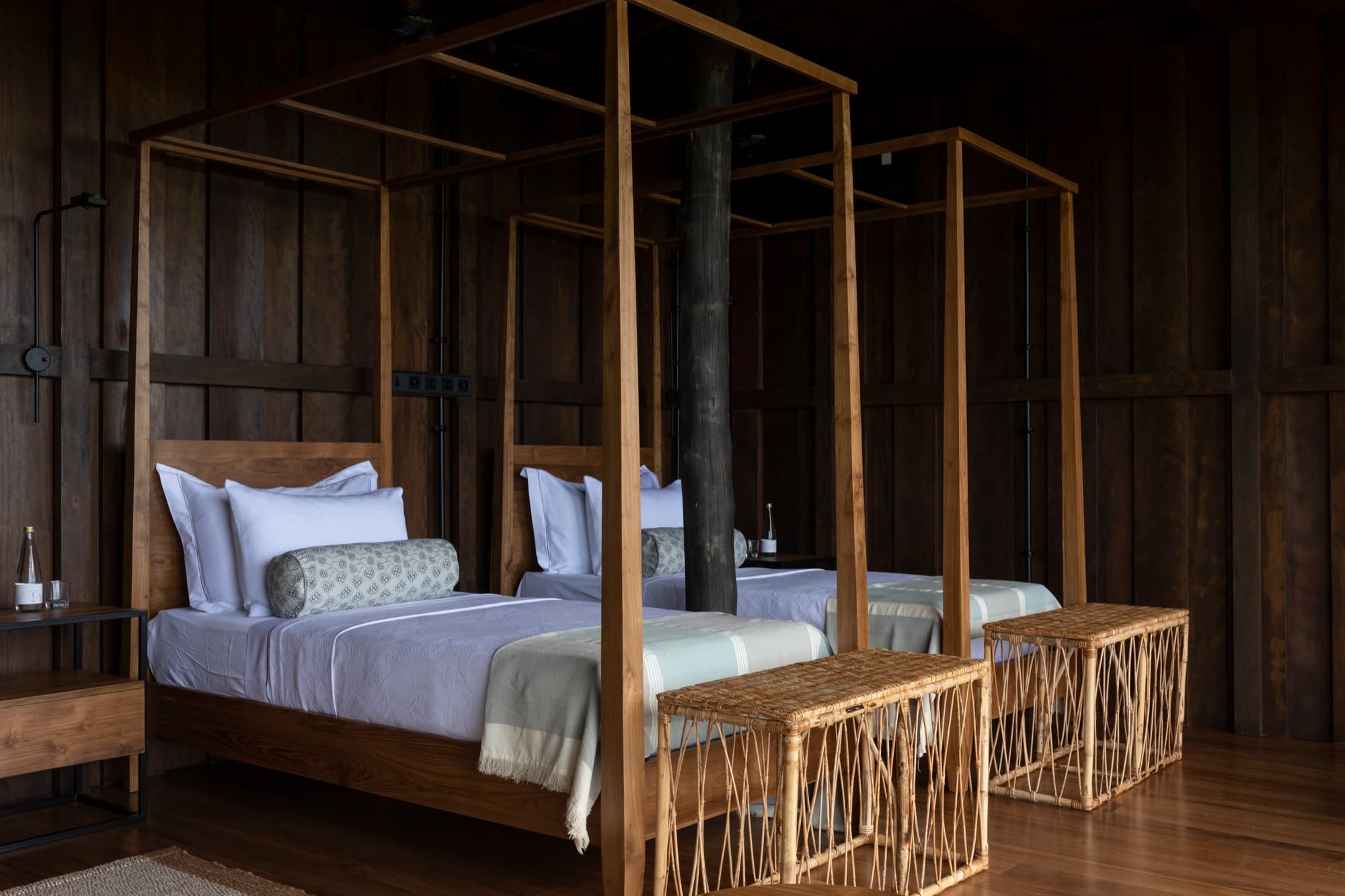 Twin room with two timber canopy beds against dark timber walls