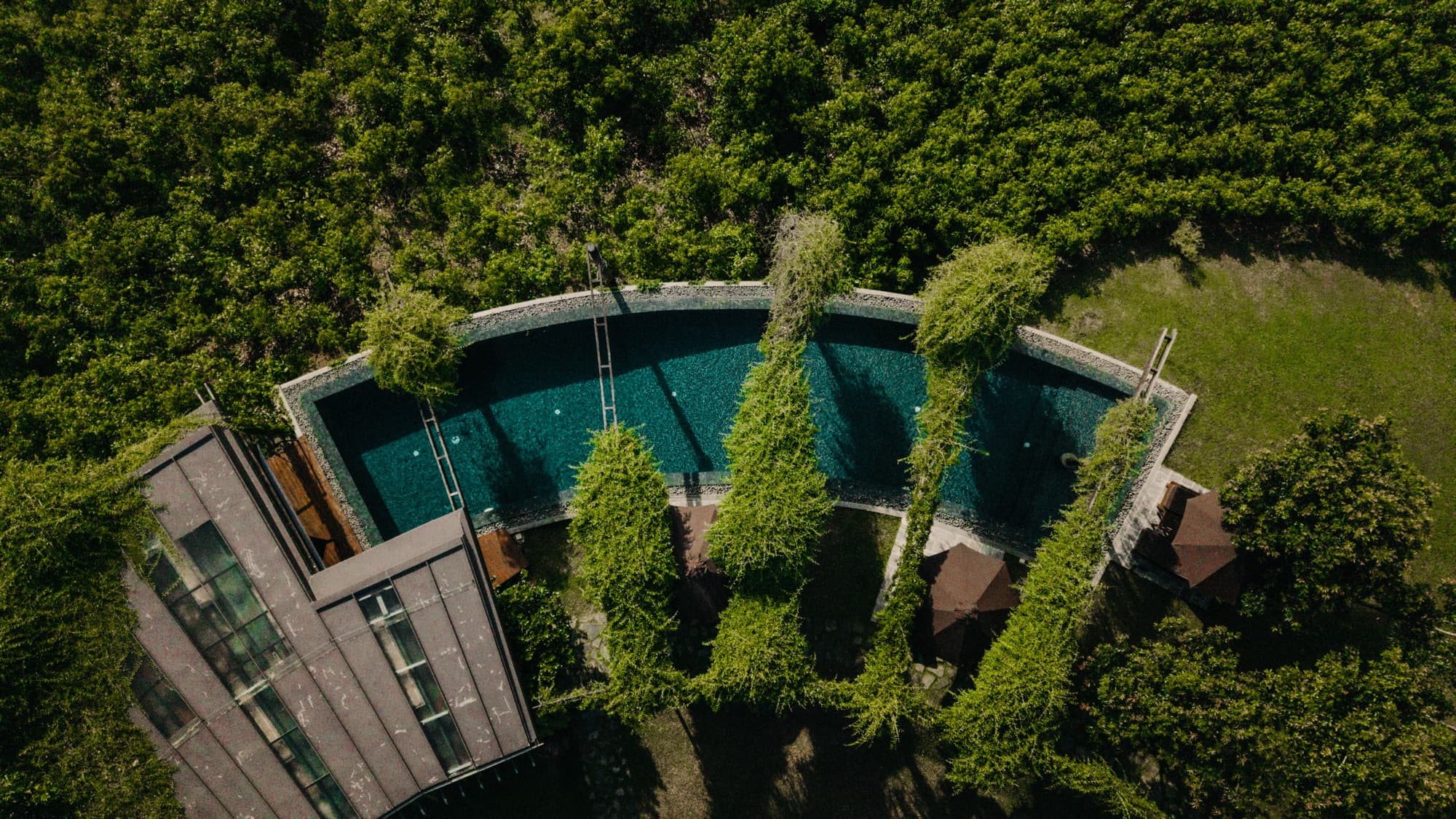 Aerial view looking down on the infinity pool and timber roofs surrounded by greenery