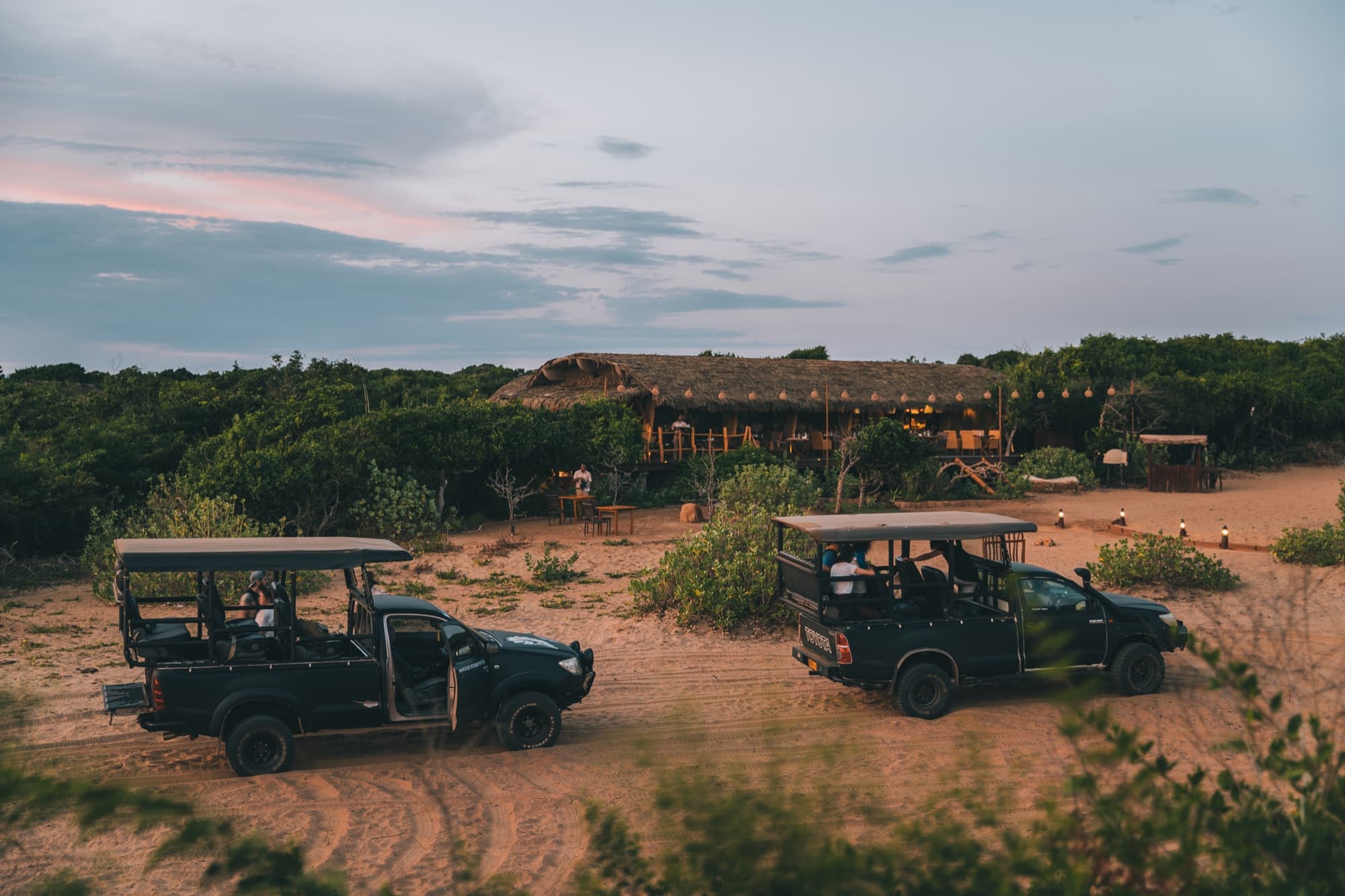 Safari jeeps parked in front of the lodge at dusk
