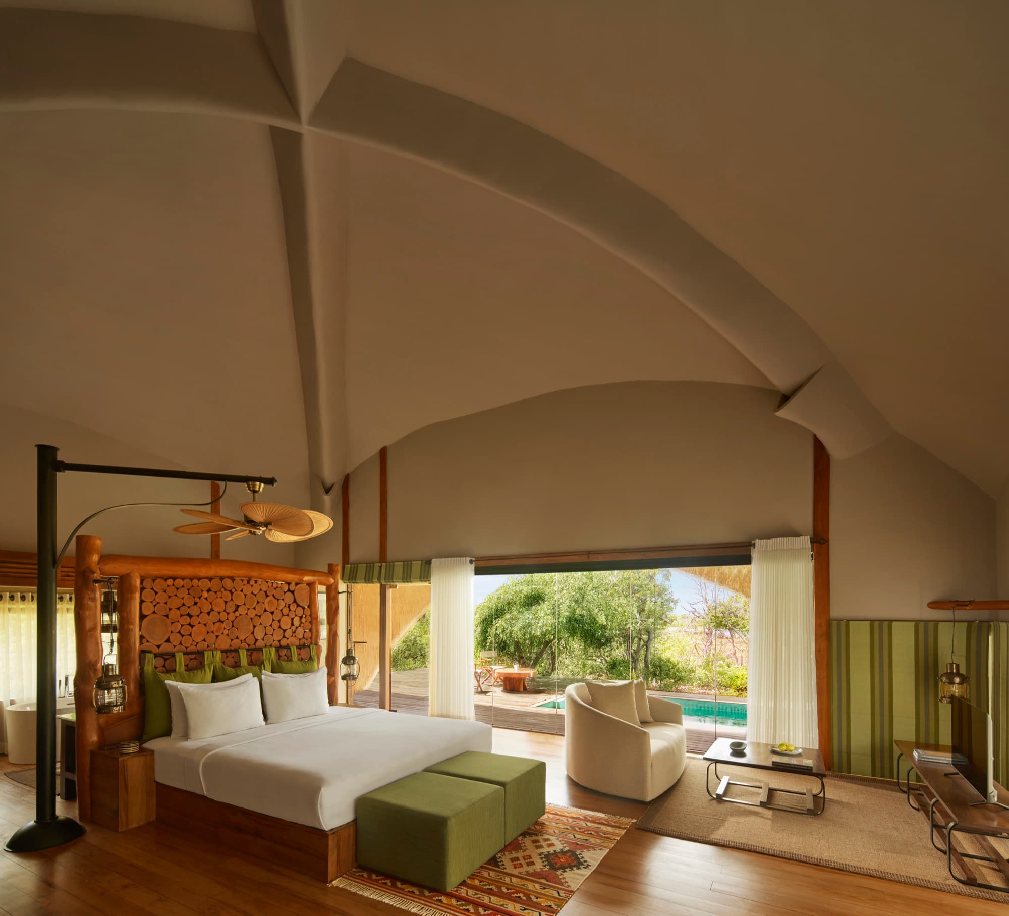 Cabin bedroom with a carved headboard and glass walls onto the bush