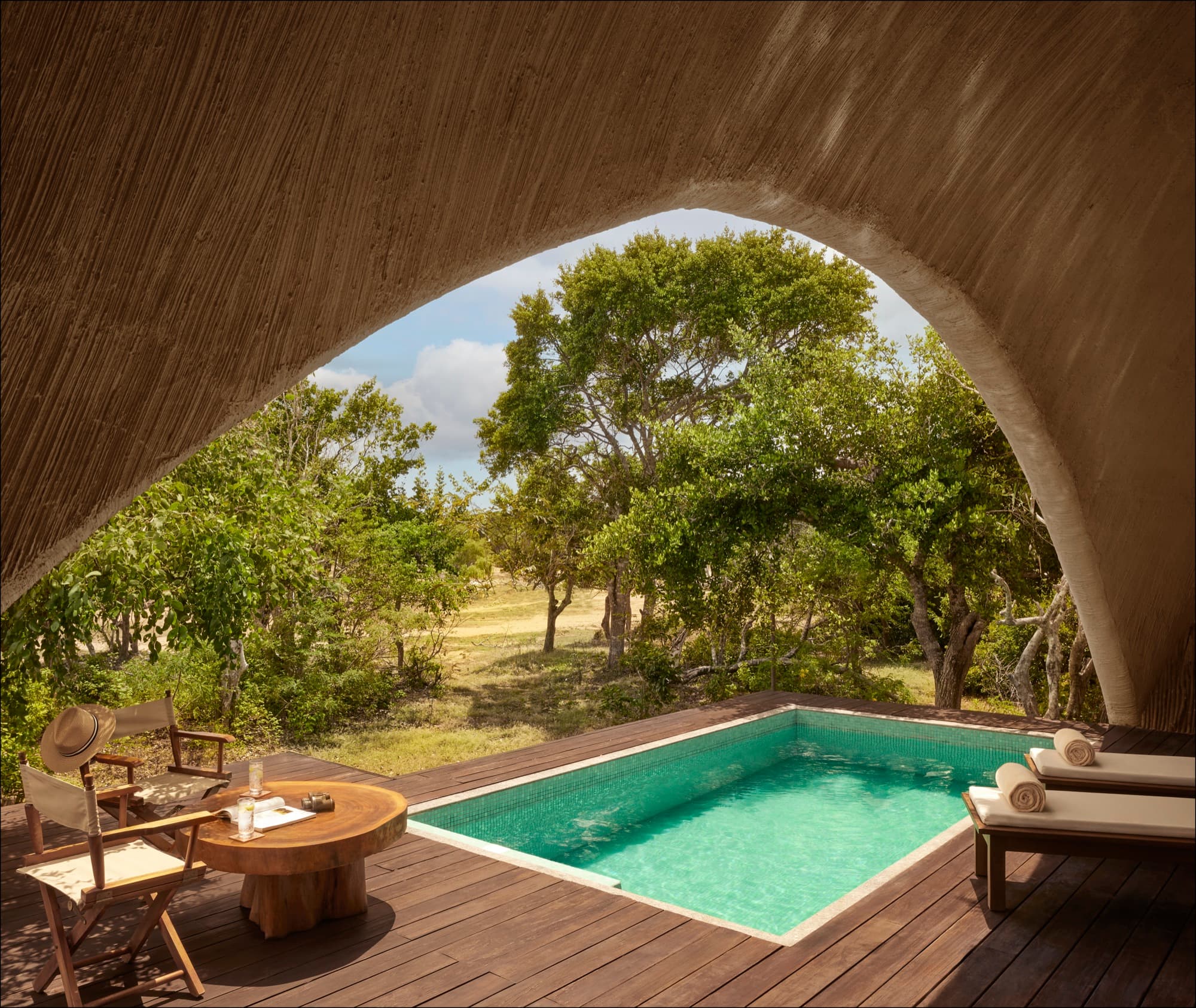 Private plunge pool on a cabin deck, framed by the curve of the thatched roof
