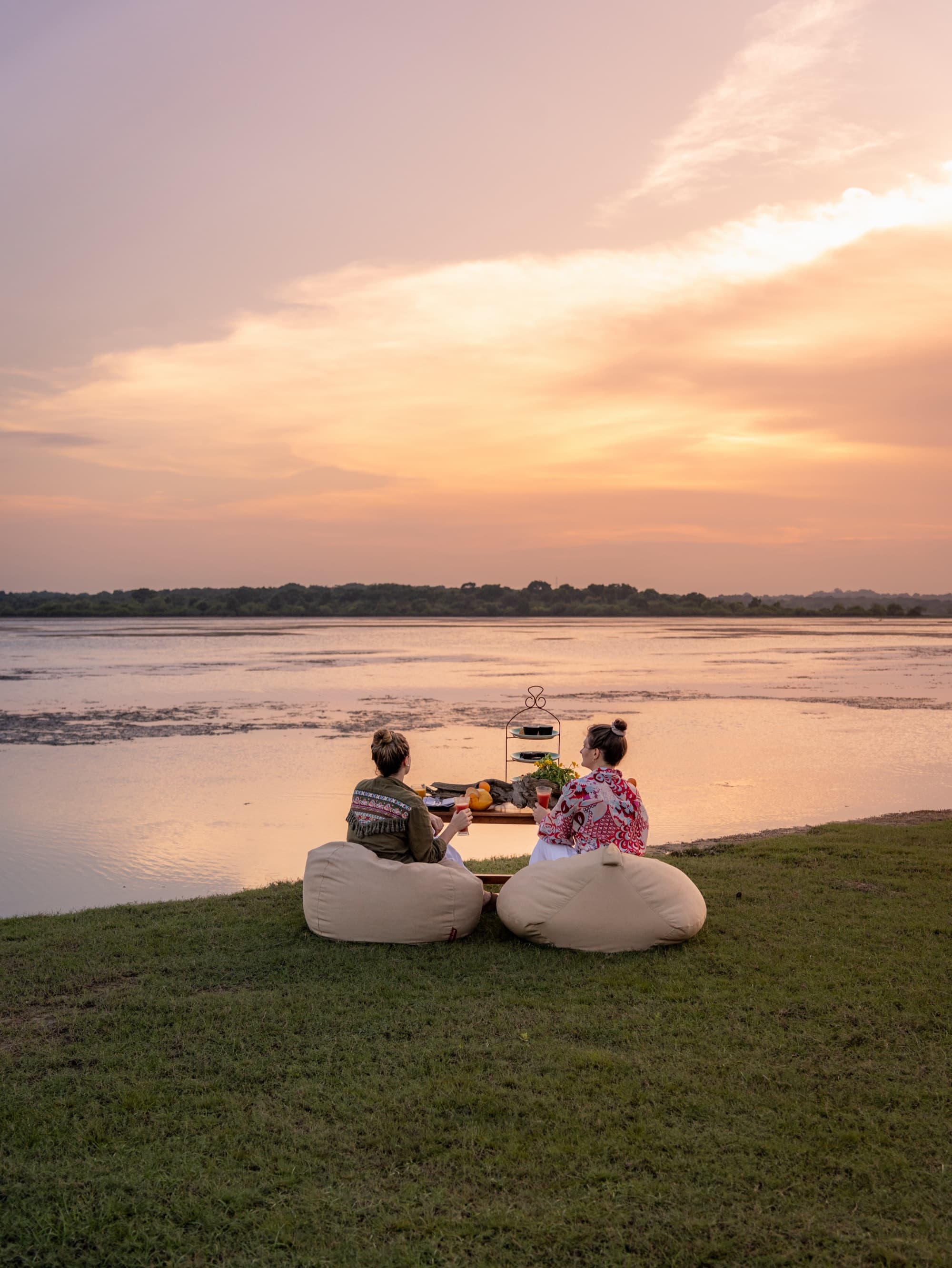 Two guests on bean bags watching the sunset over a Yala lagoon
