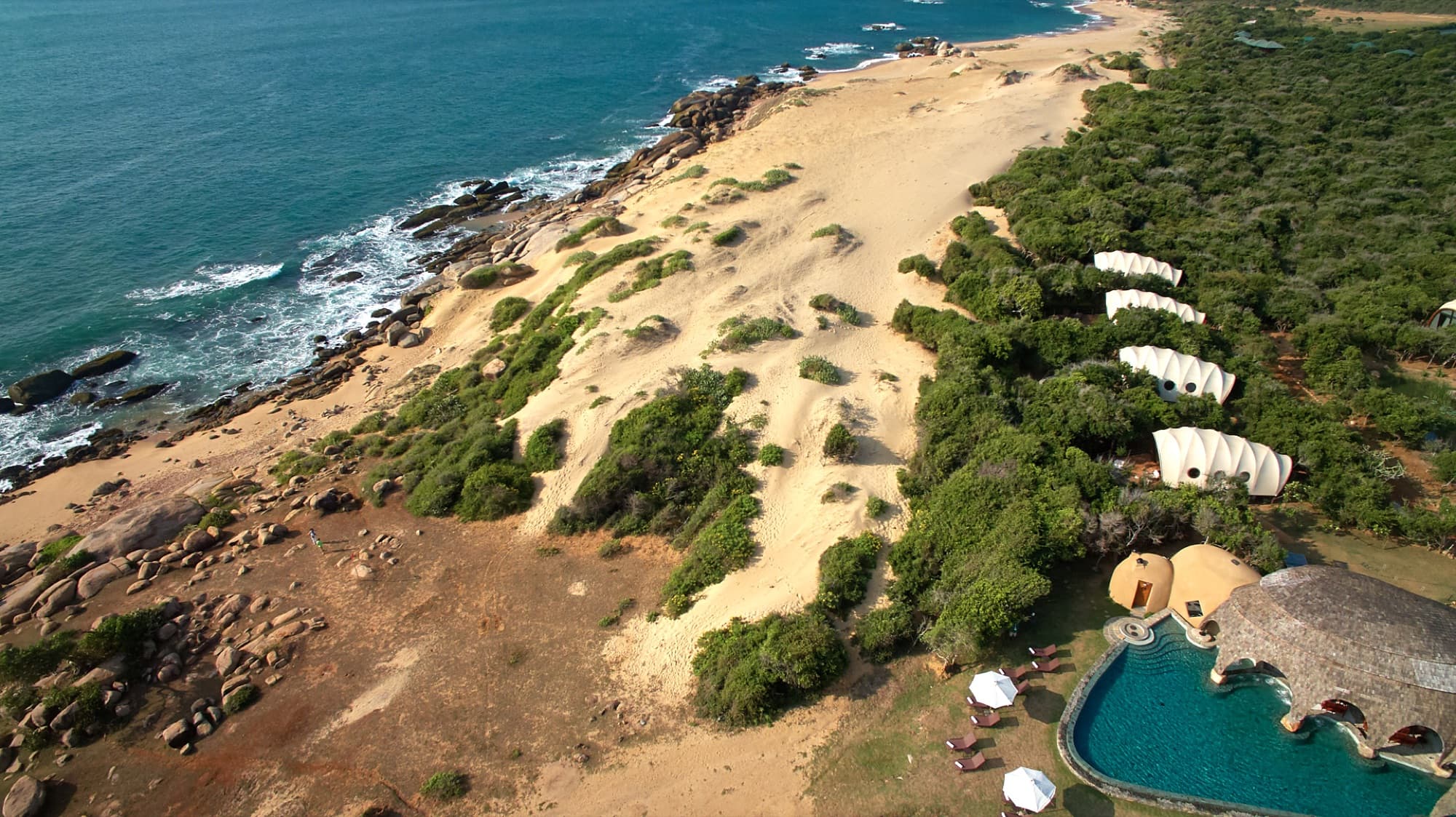 Wide aerial view of Wild Coast Tented Lodge between the dunes, beach and Indian Ocean