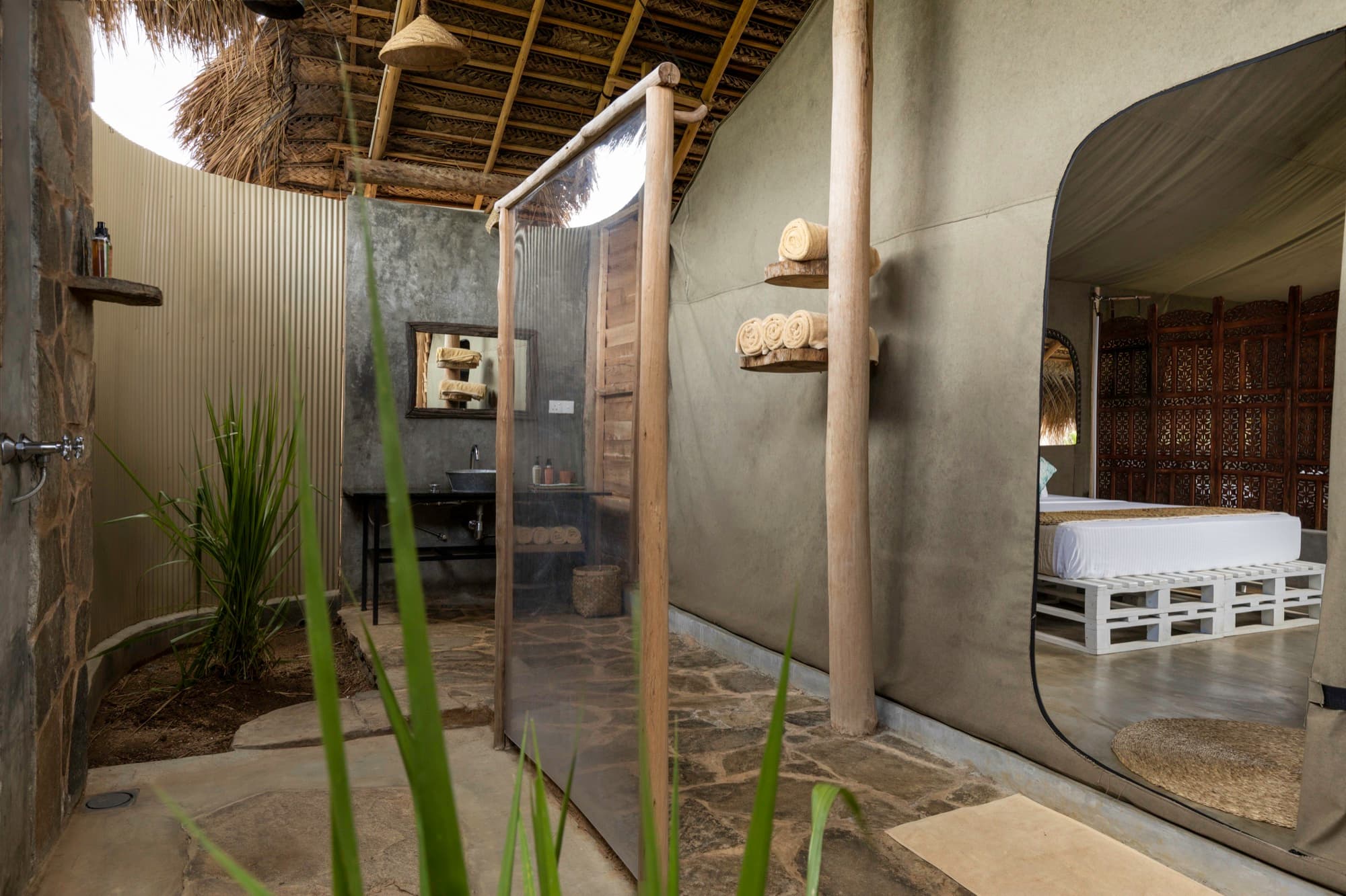 Deluxe Tent open-air bathroom with concrete sink and outdoor shower under the thatched roof