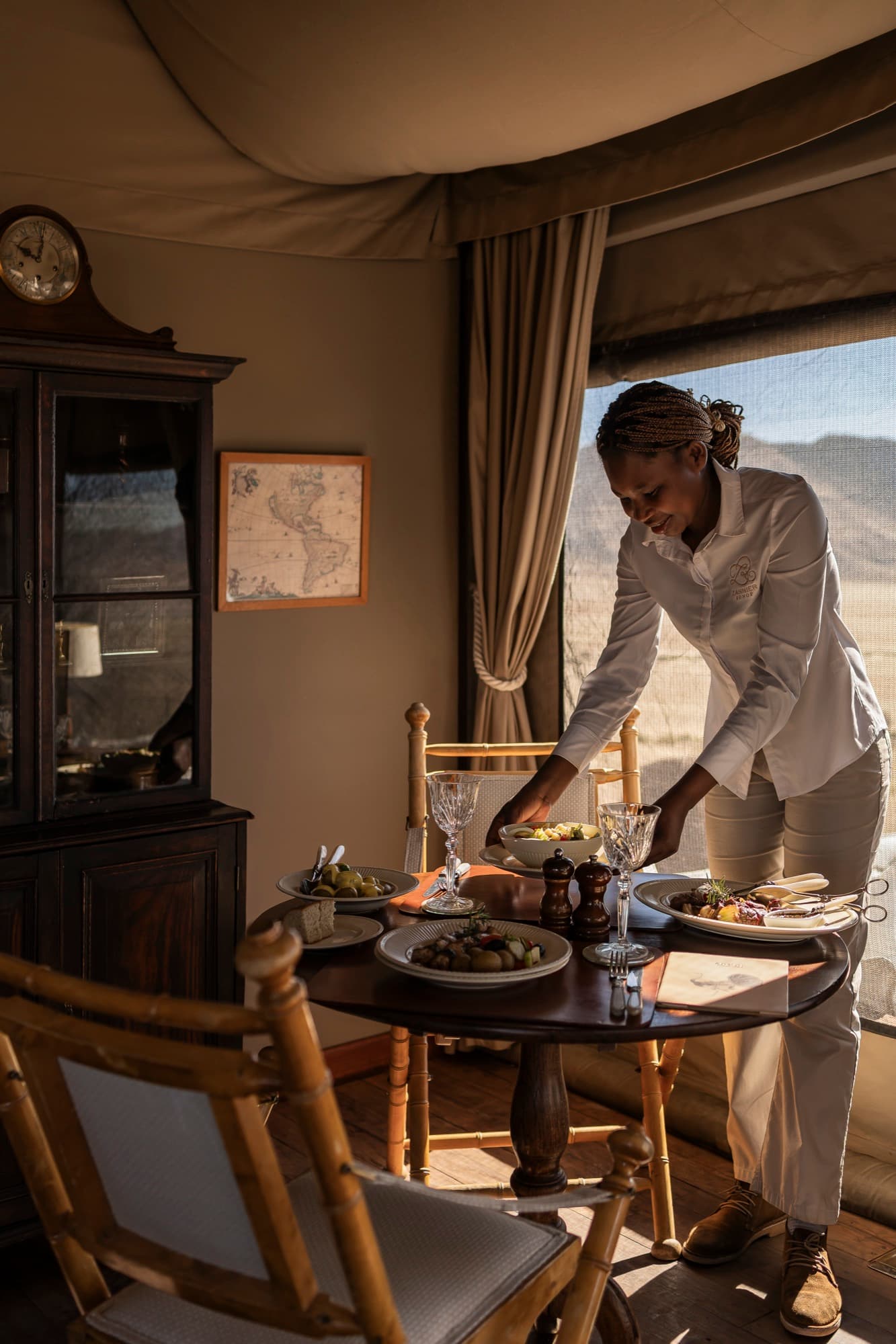 A table being set by a window open to the desert