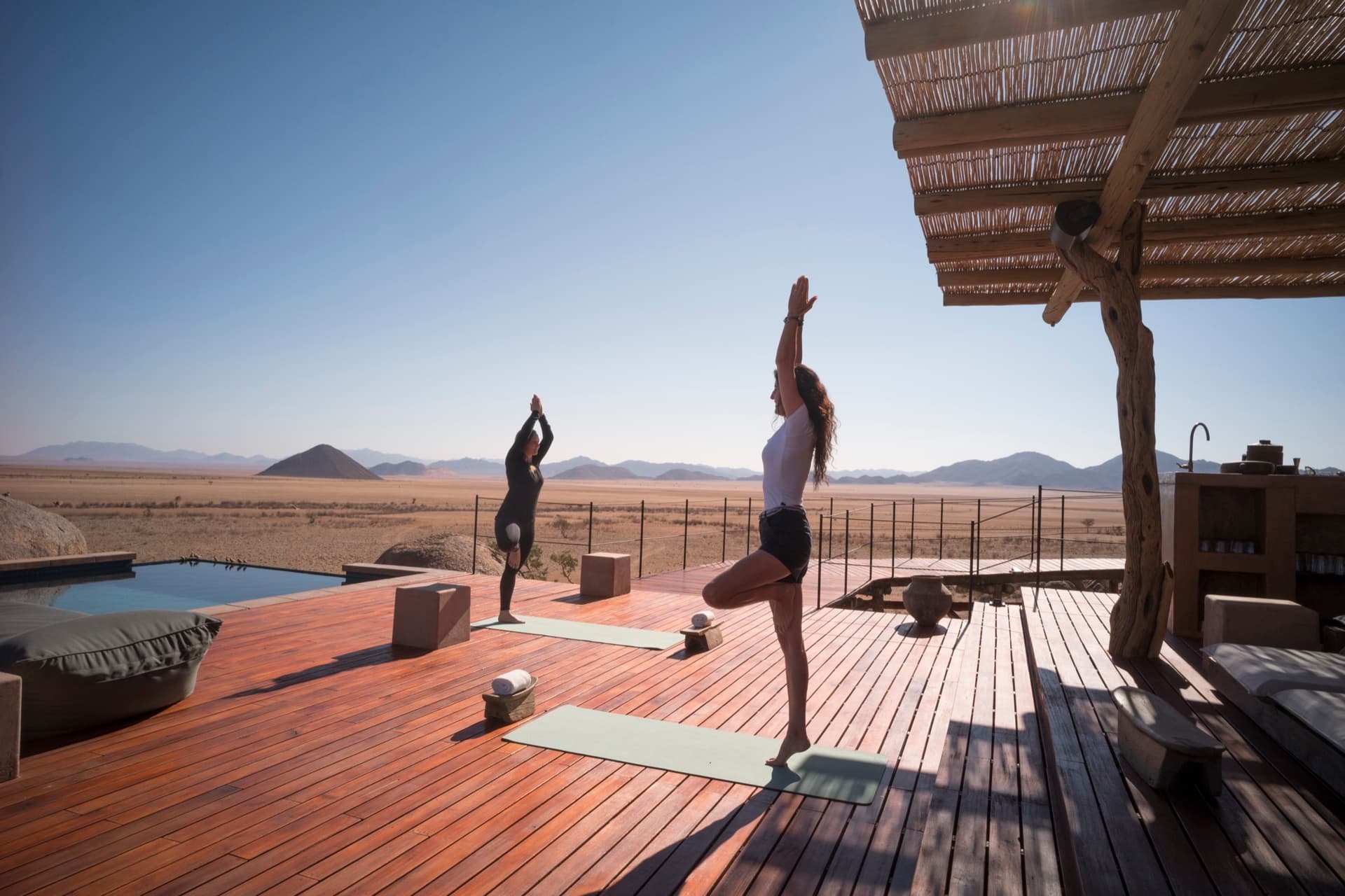 Yoga on the wooden deck by the pool, the desert behind