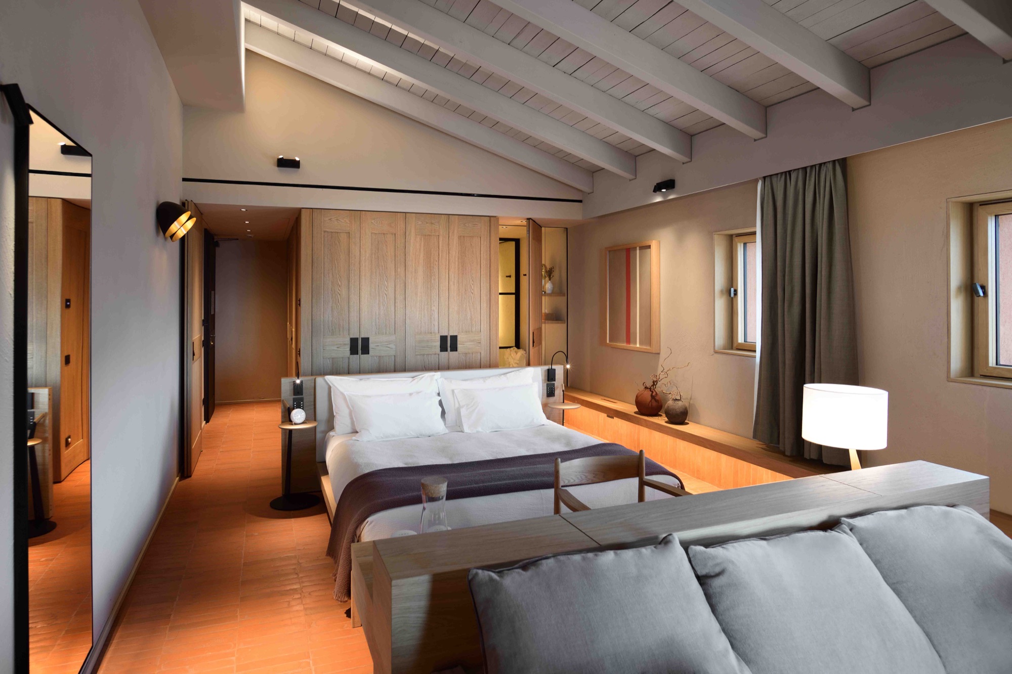 Suite under a beamed ceiling, with a sofa facing the bed
