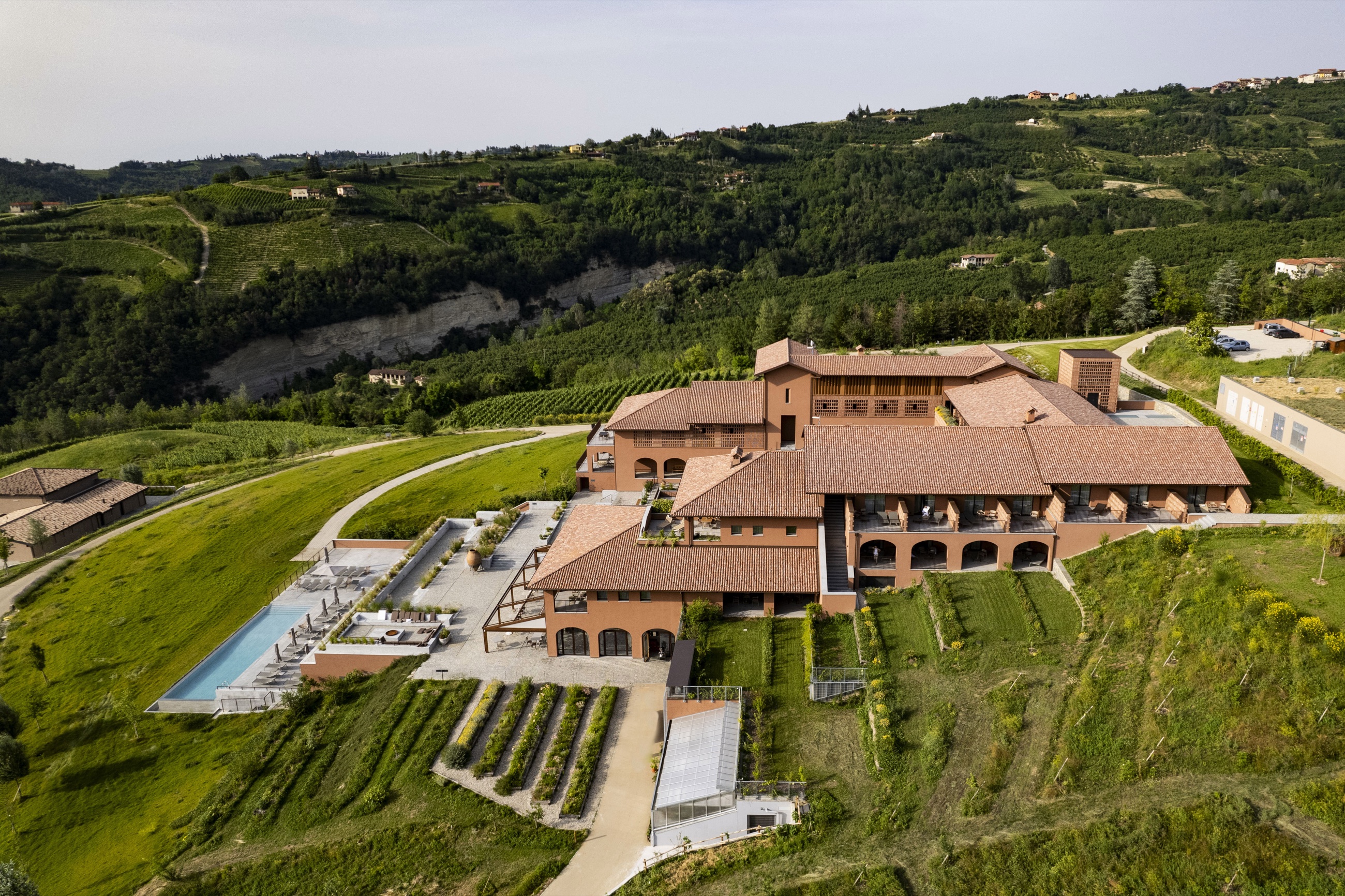 Aerial view of Casa di Langa and its infinity pool among vineyards and woods — boutique hotel in the Langhe, Piedmont