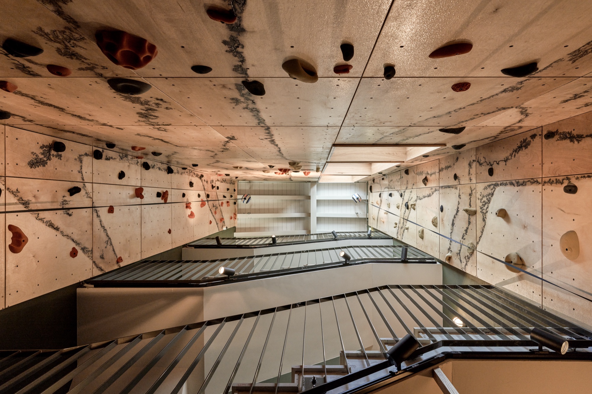 Climbing wall rising up the stairwell, seen from below
