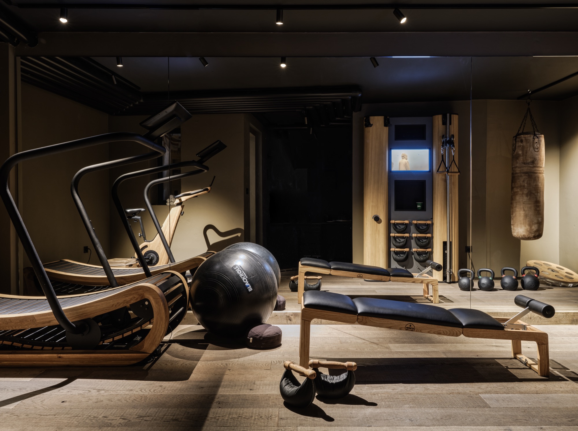 Gym with a curved treadmill, a weight bench and kettlebells