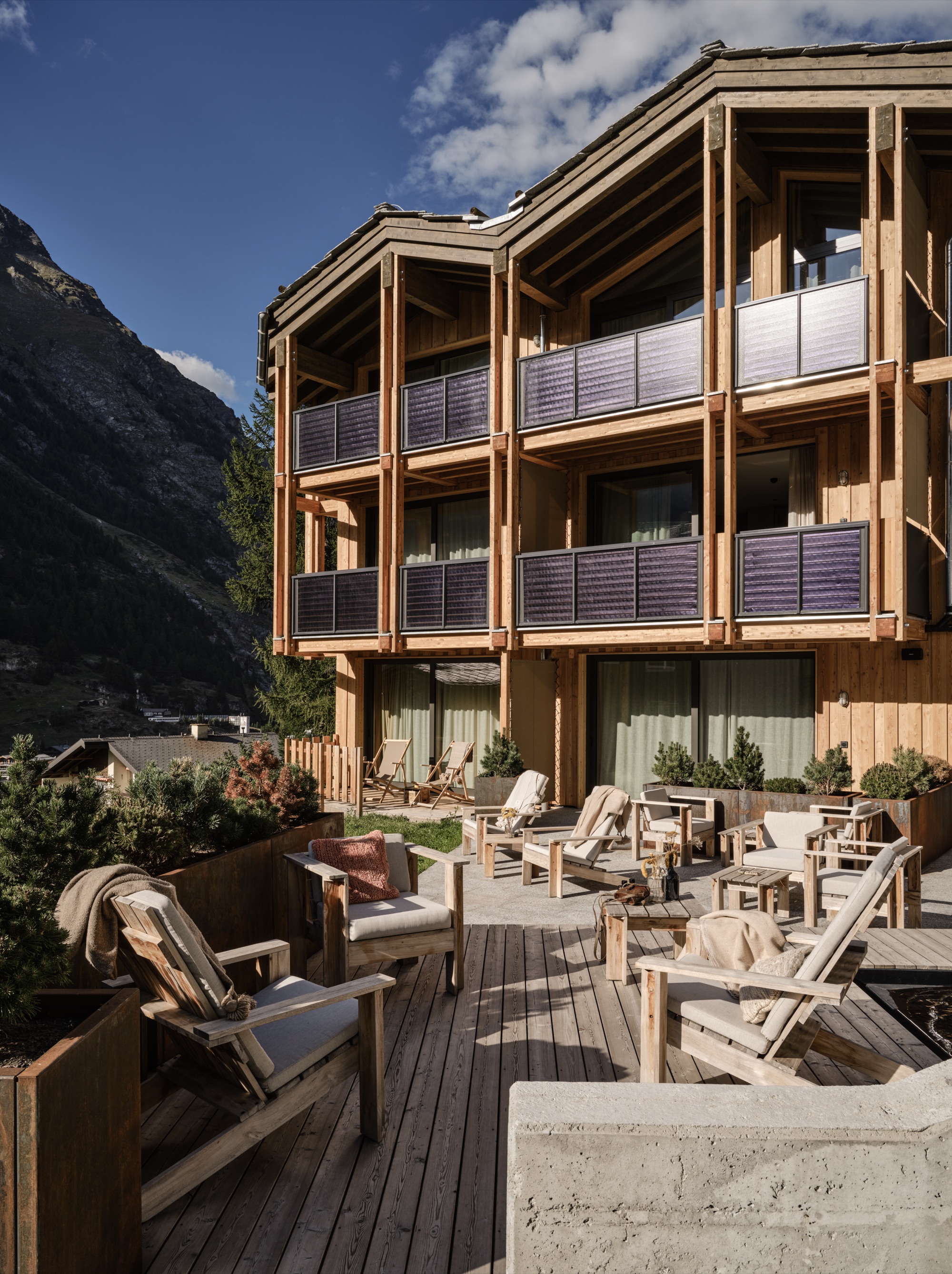 A timber lodge with balconies above a terrace of loungers