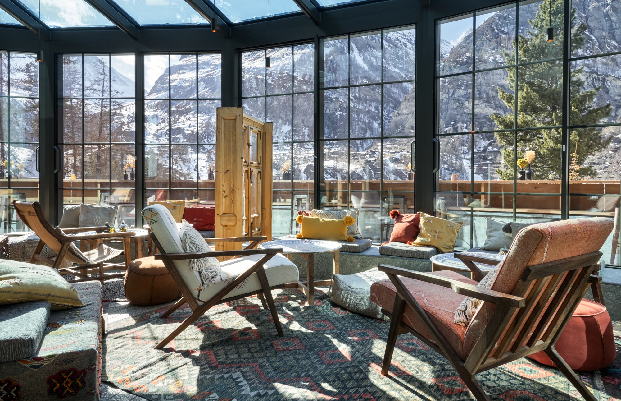 Glass-walled lounge with armchairs and views of snowy peaks