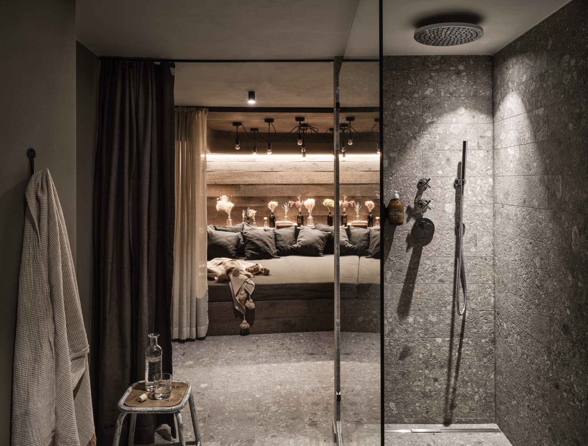 Stone walk-in shower next to a cushioned seating nook