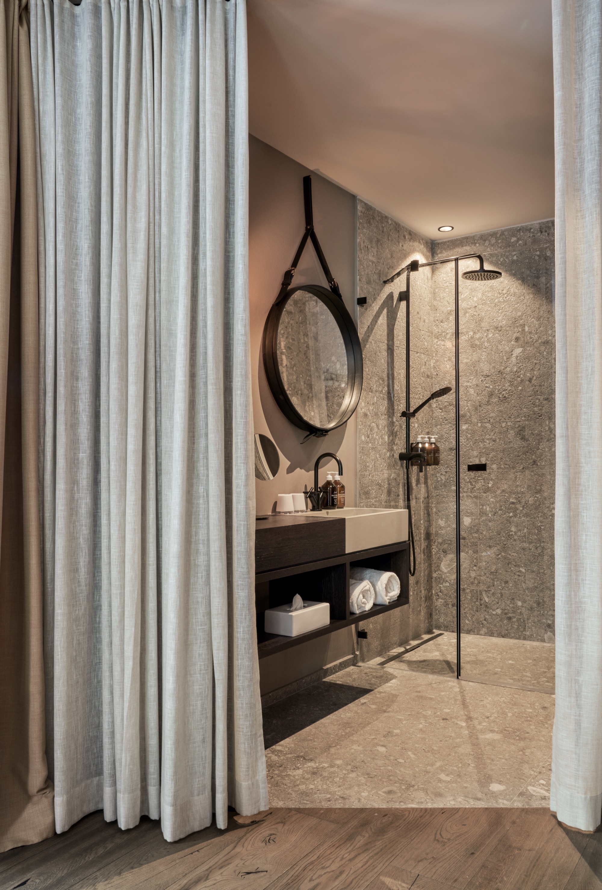 Shower behind a linen curtain, with a round mirror