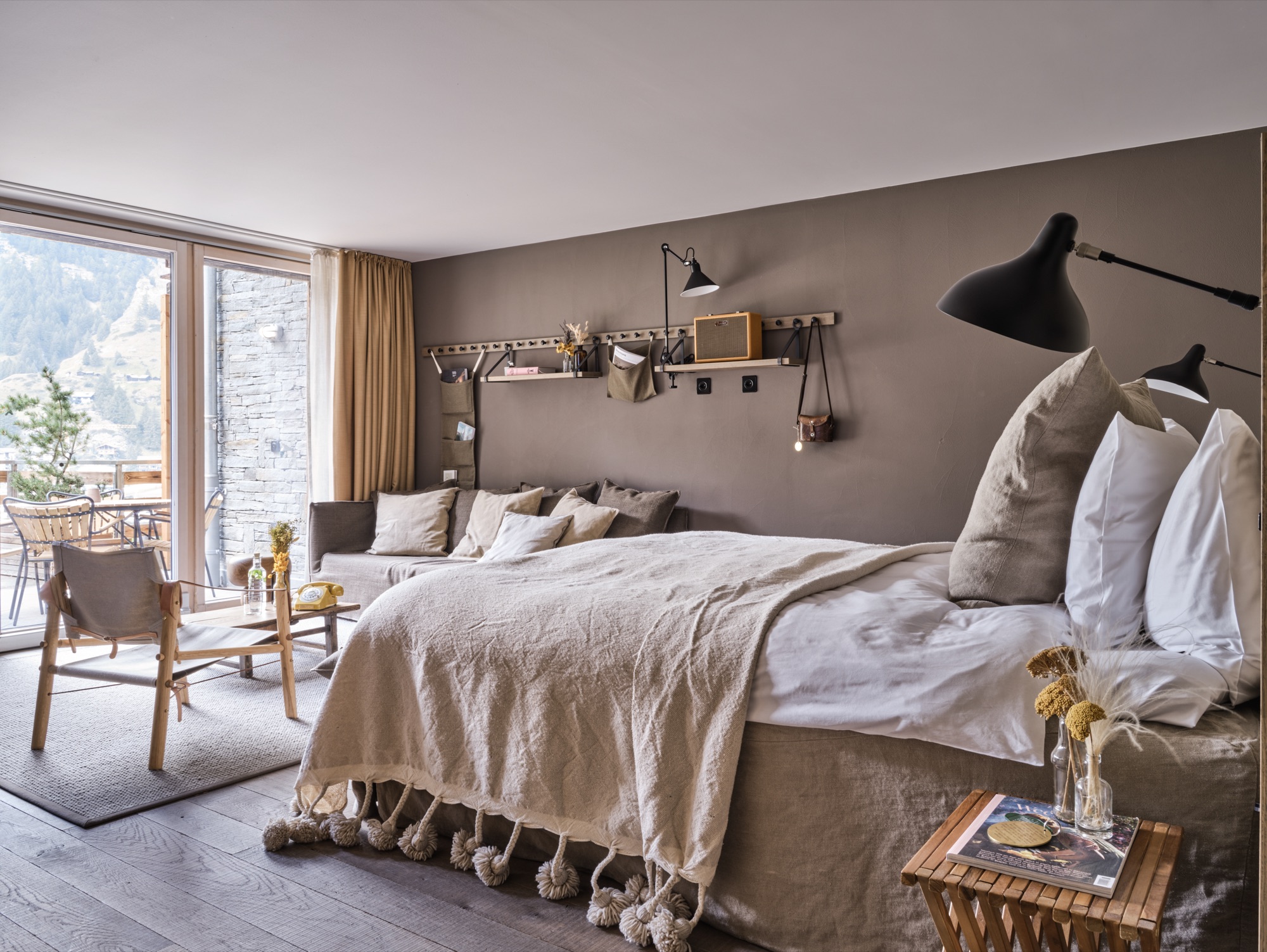 Bedroom with a wide bed, a sofa and windows onto a balcony