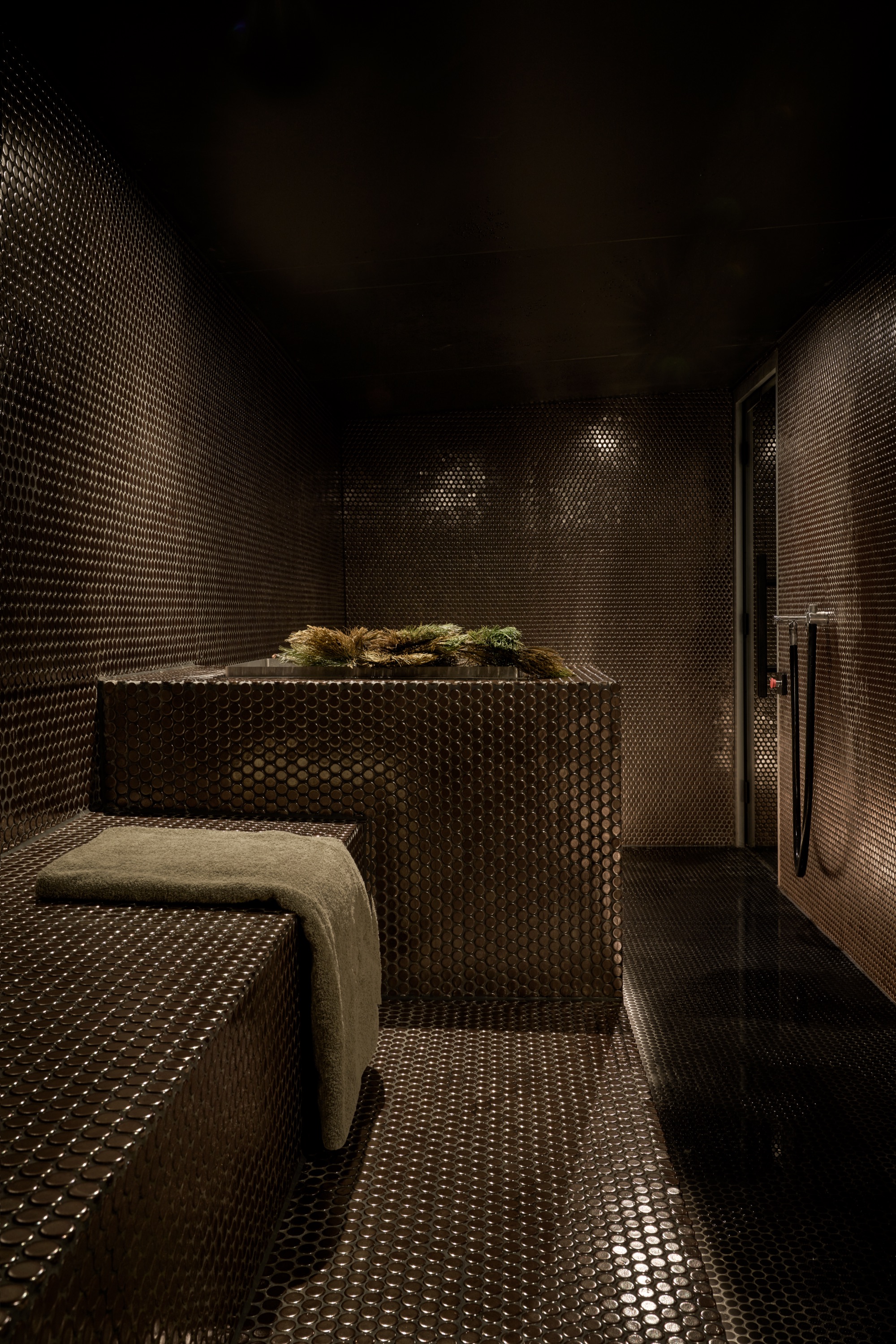 Steam room lined with dark mosaic tiles