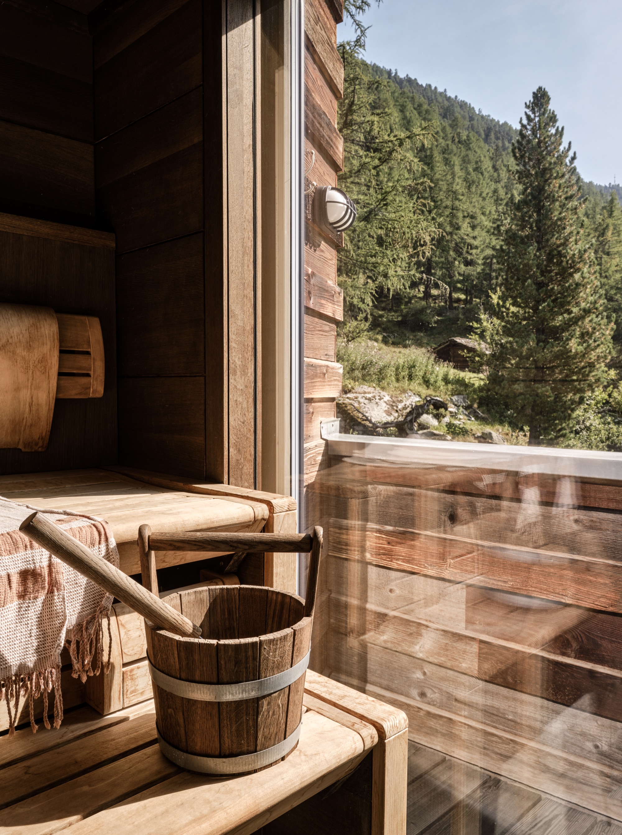 Sauna with a wooden bucket and a window onto the forest