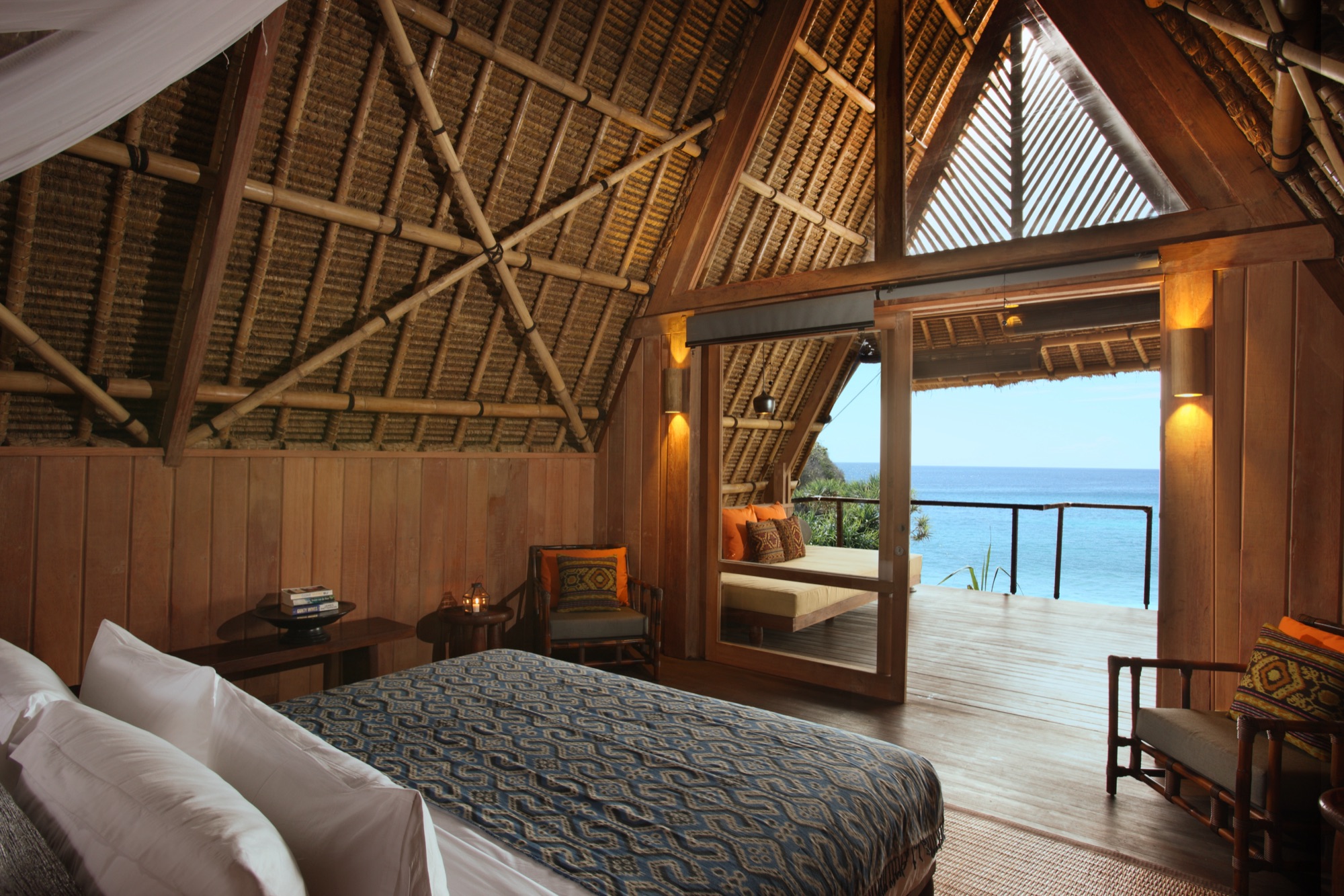 Lodge bedroom with bamboo thatched ceiling and sea view through open sliding doors