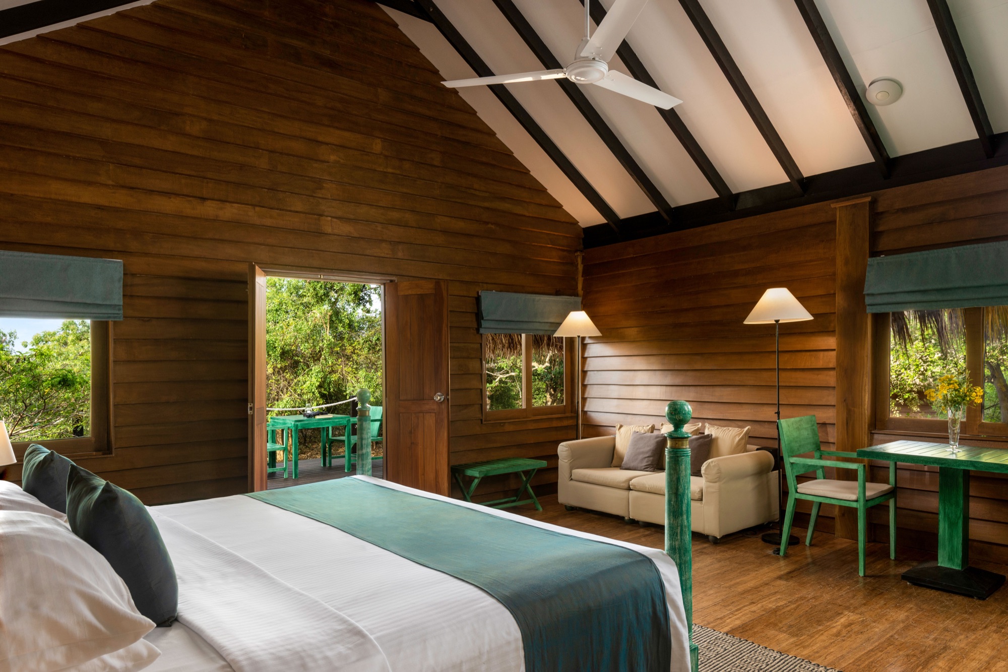 Open cabin interior with high pitched ceiling, ceiling fan and view onto the terrace