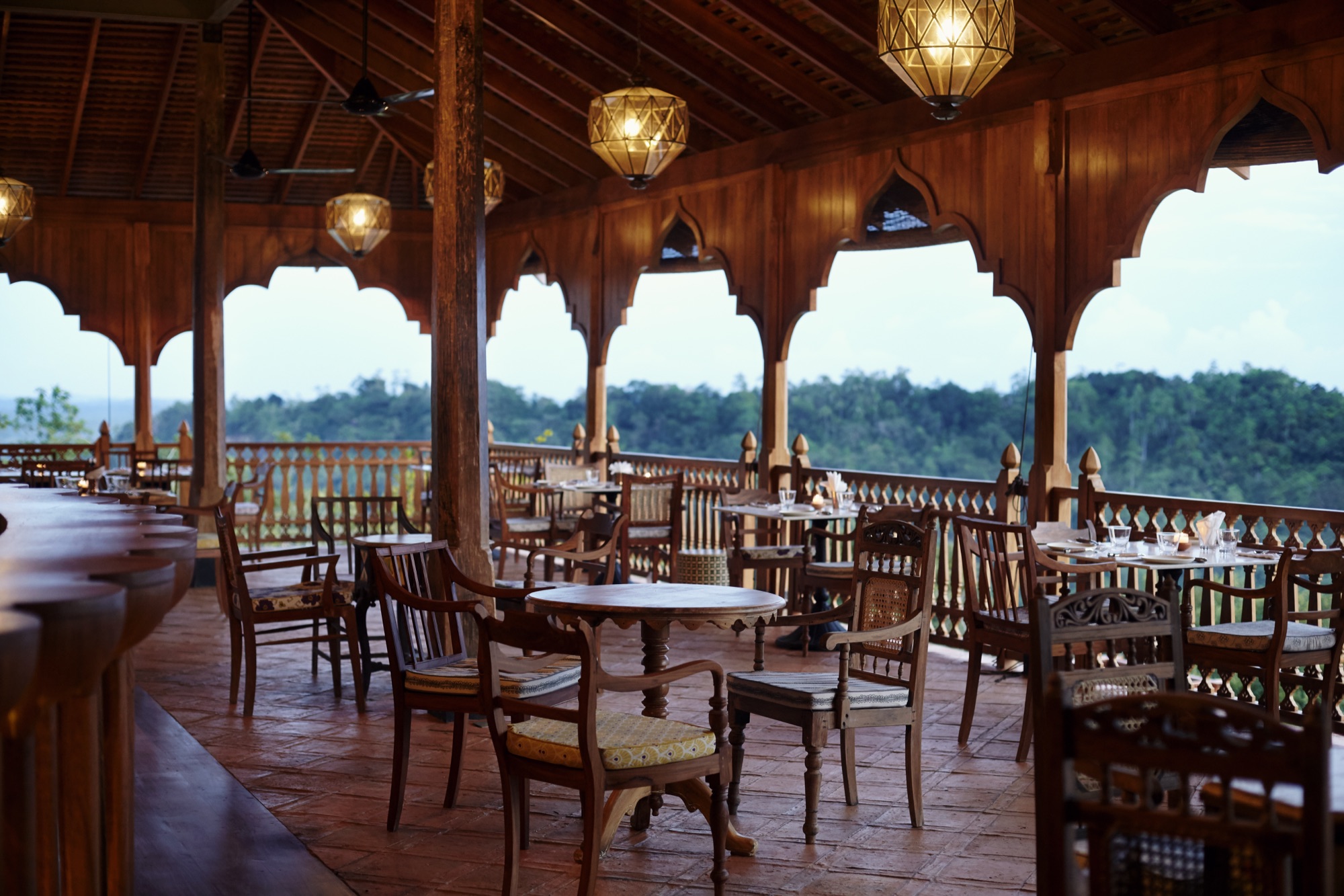 Timber restaurant terrace under Moorish arches at dusk, hills beyond