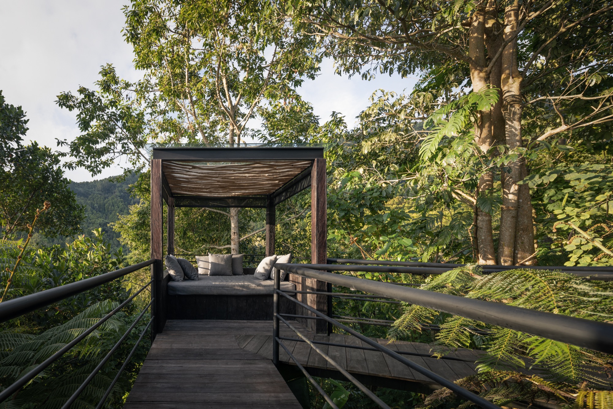 Cushioned daybed cabana on a boardwalk platform projecting into the forest canopy
