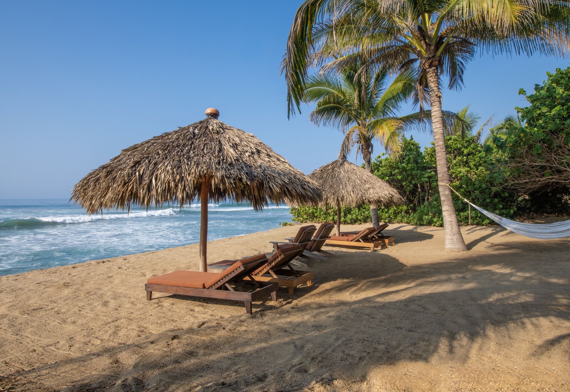 Thatched umbrellas, loungers and a hammock on the beach