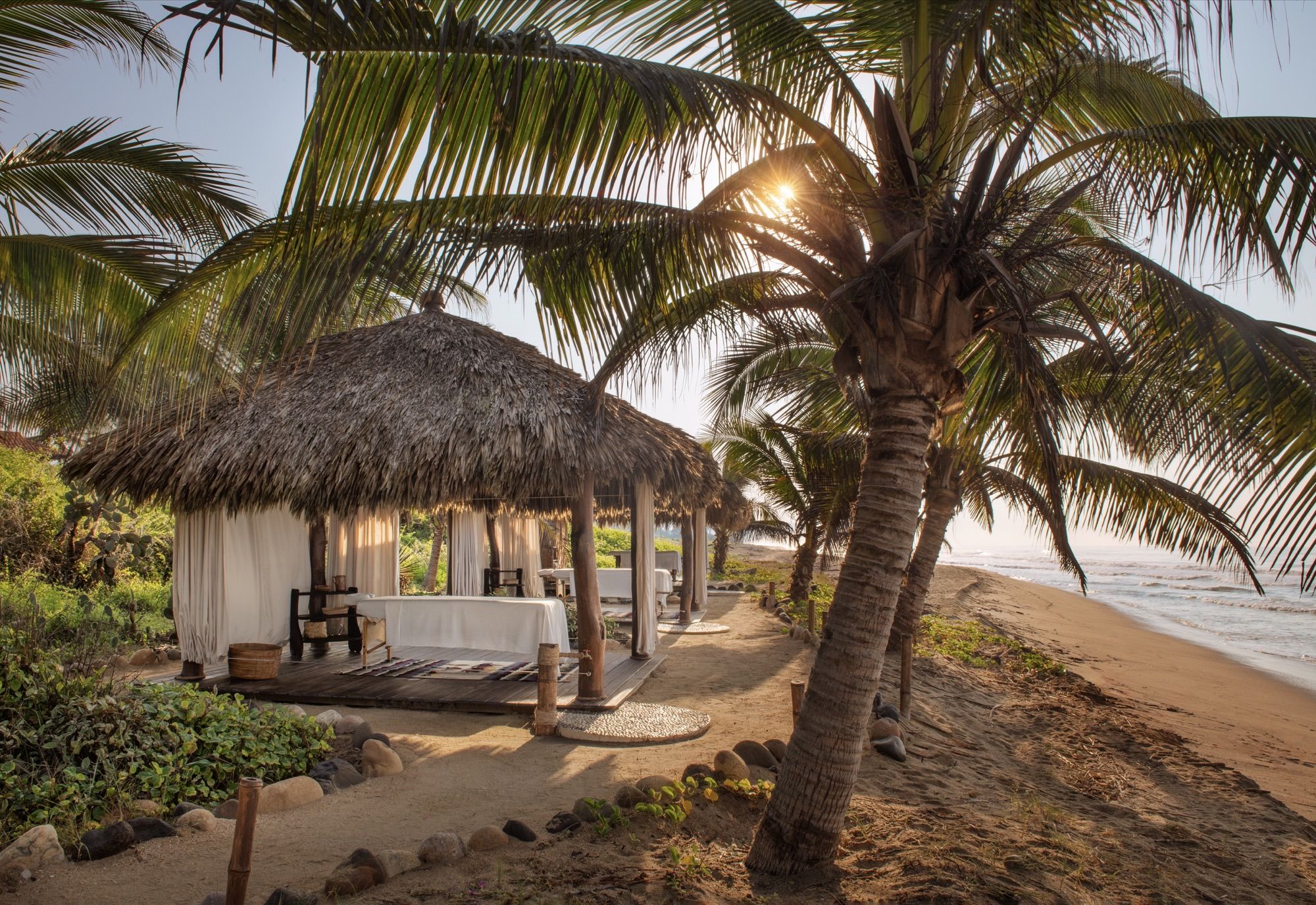 Massage hut thatched with palm, between the palms and the beach