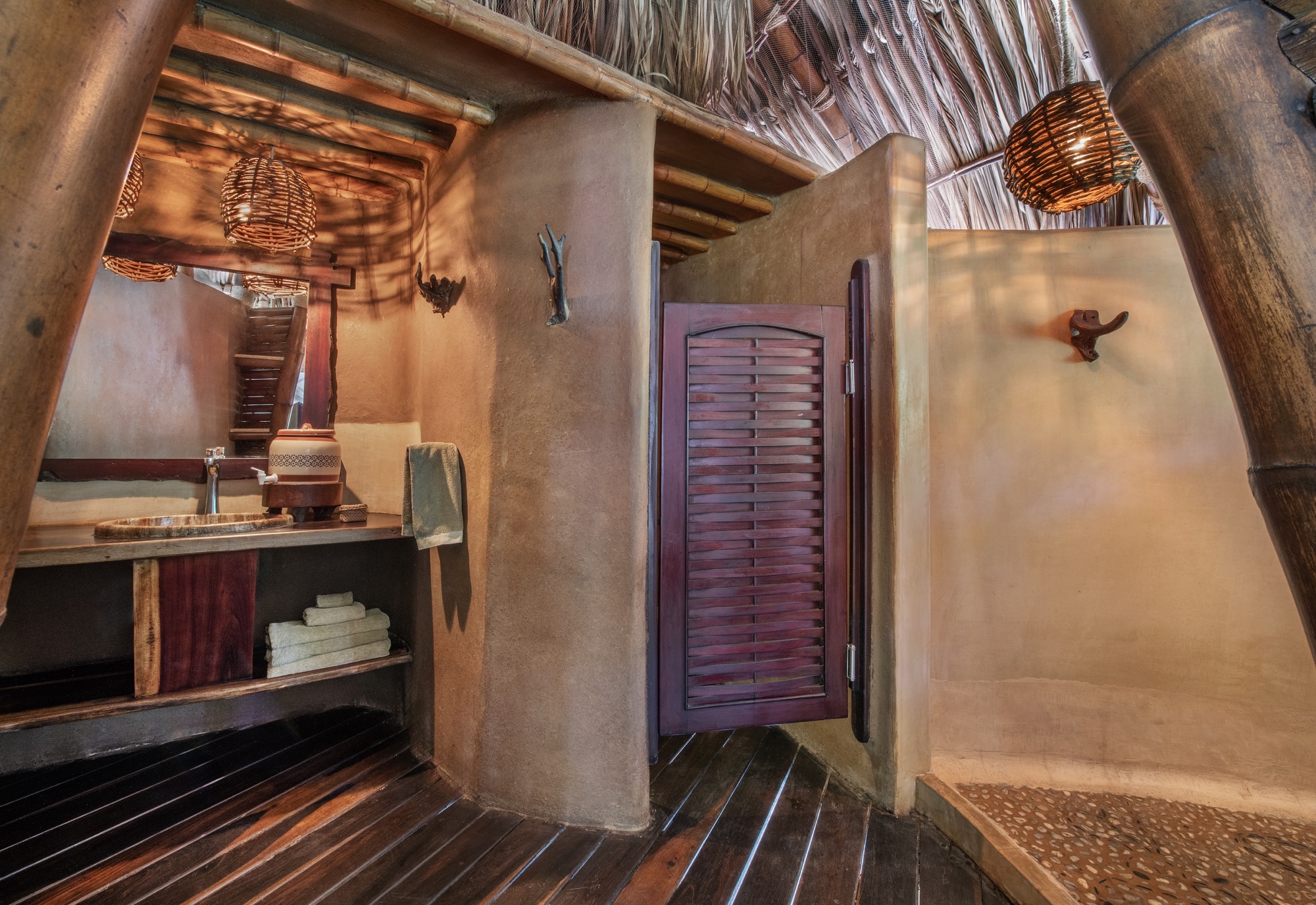 Deluxe Suite bathroom with earthen walls and a wooden door