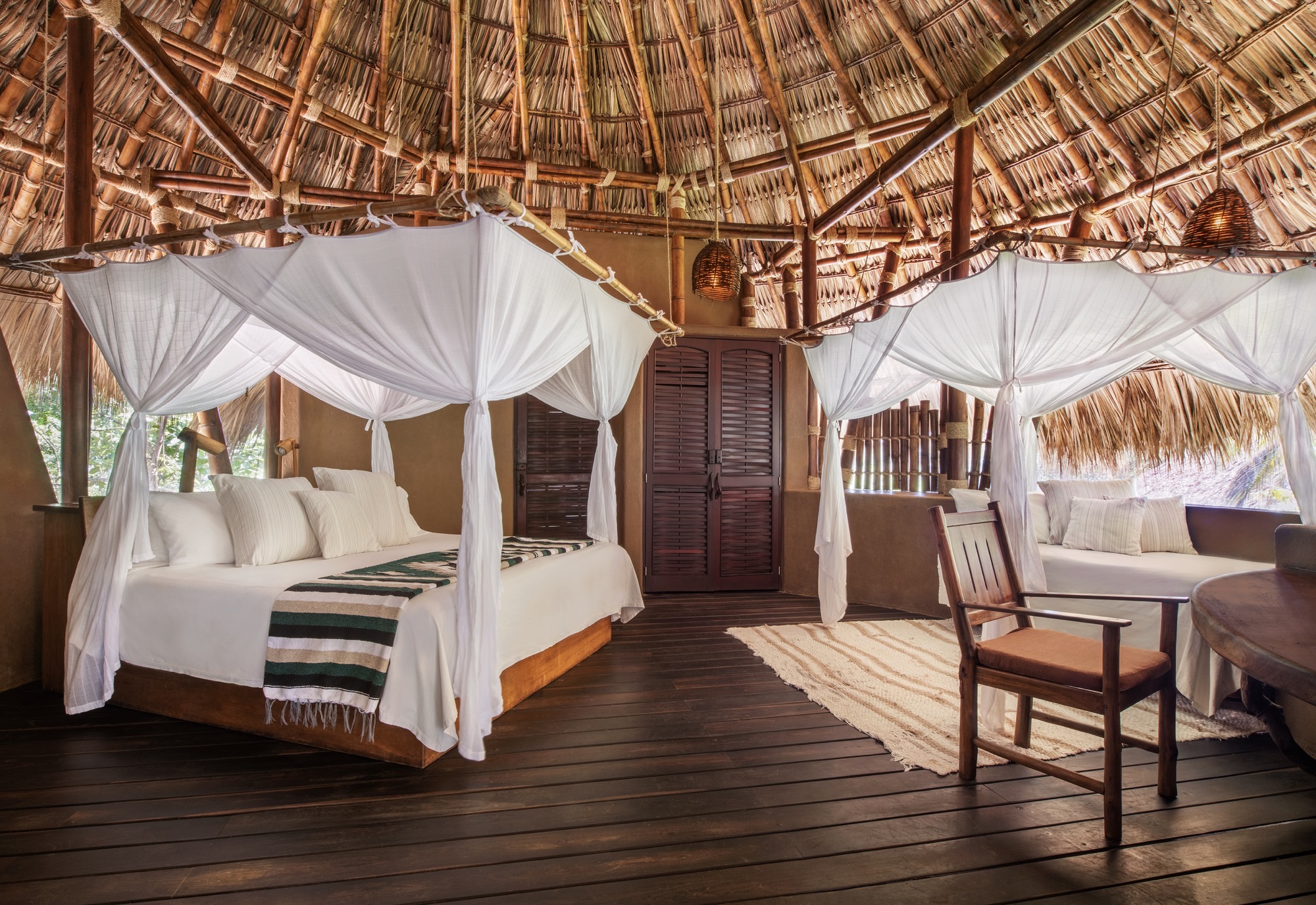 Deluxe Suite with two mosquito-net beds under a thatched roof
