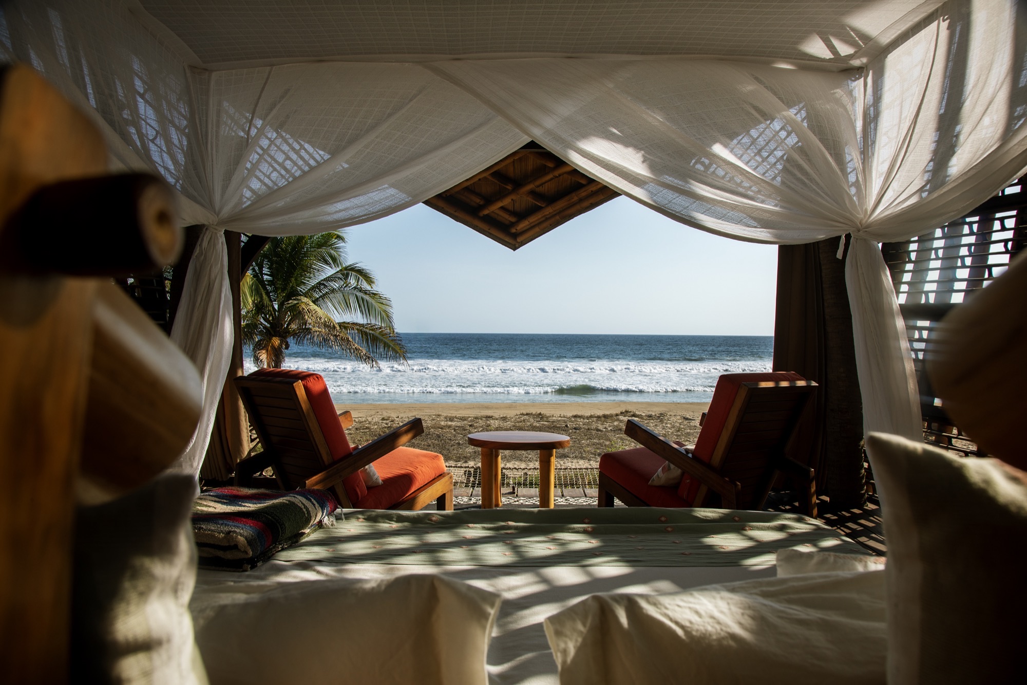 View of the beach from the bed of a Manta treehouse
