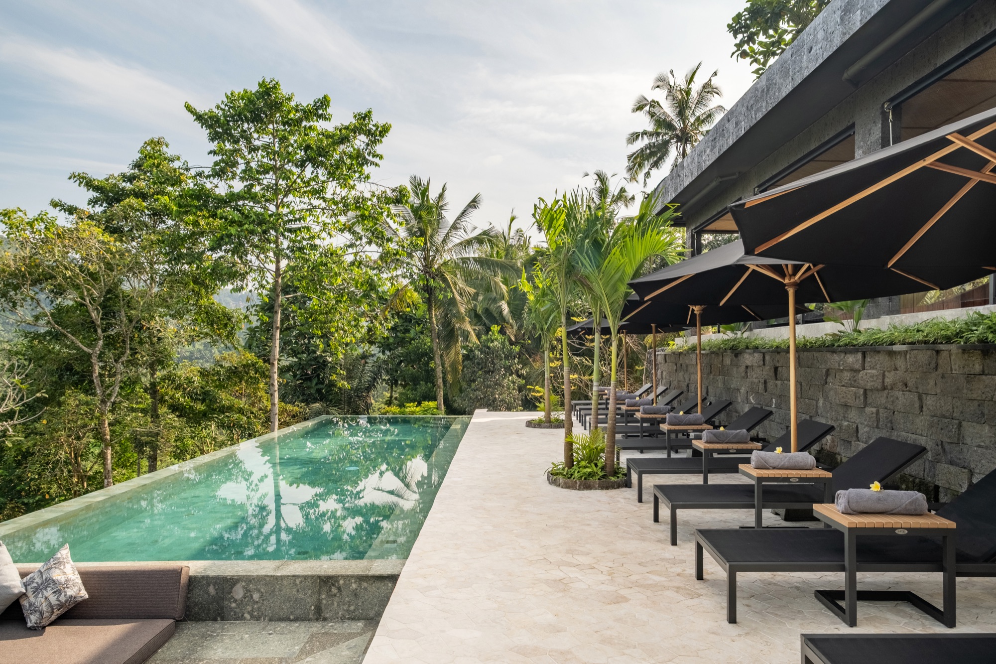 Wellness pool area with sun loungers and tropical vegetation at Samanvaya