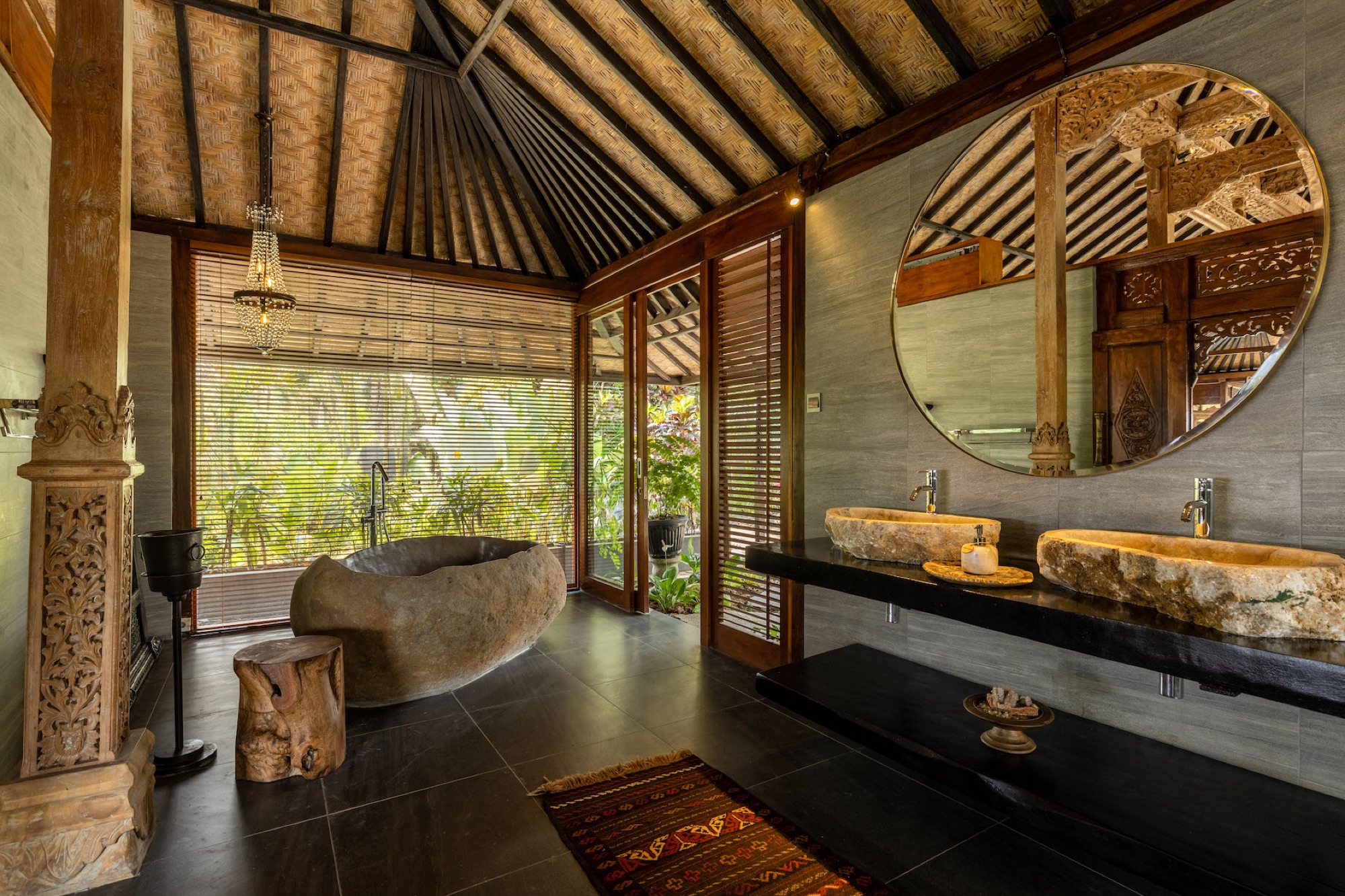 Joglo villa bathroom with carved wooden pillars and traditional Balinese stone finishes