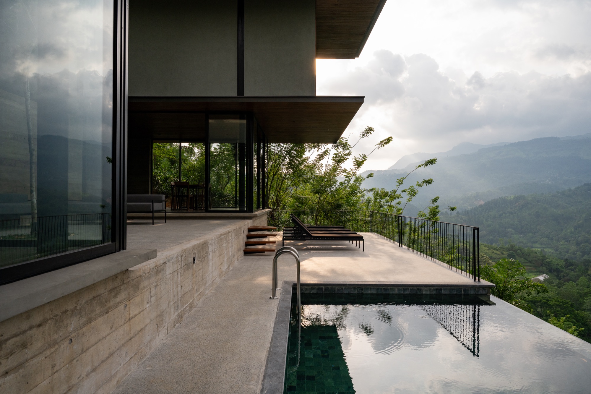 Private plunge pool and loungers on a villa terrace above a misty mountain valley