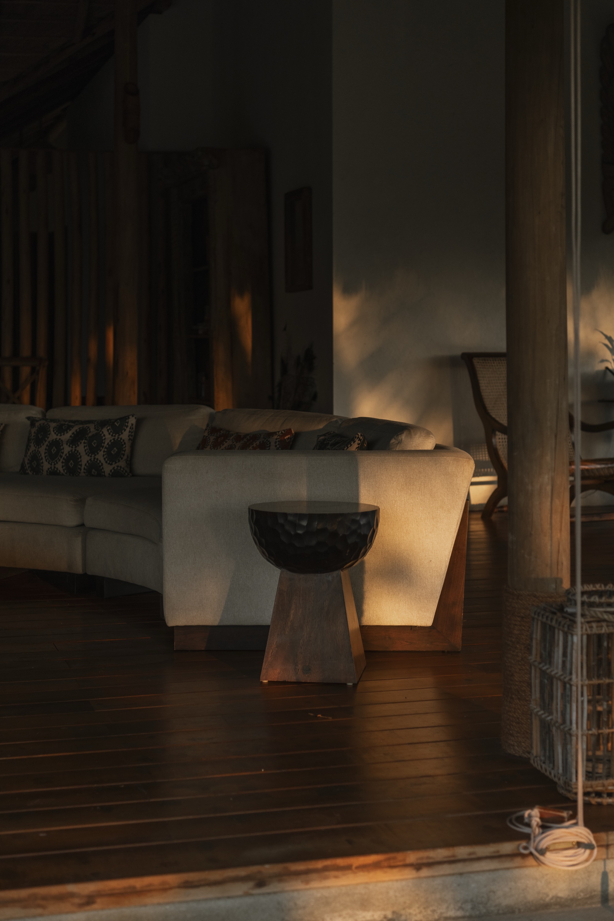 Living area at golden hour with a pale sofa and dark timber floor