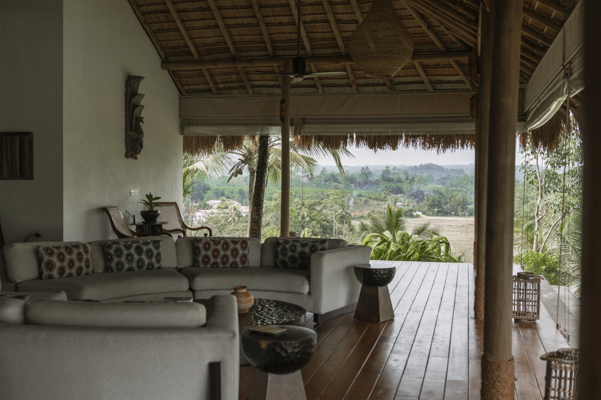 Covered lounge with sofas opening onto a timber deck and valley views