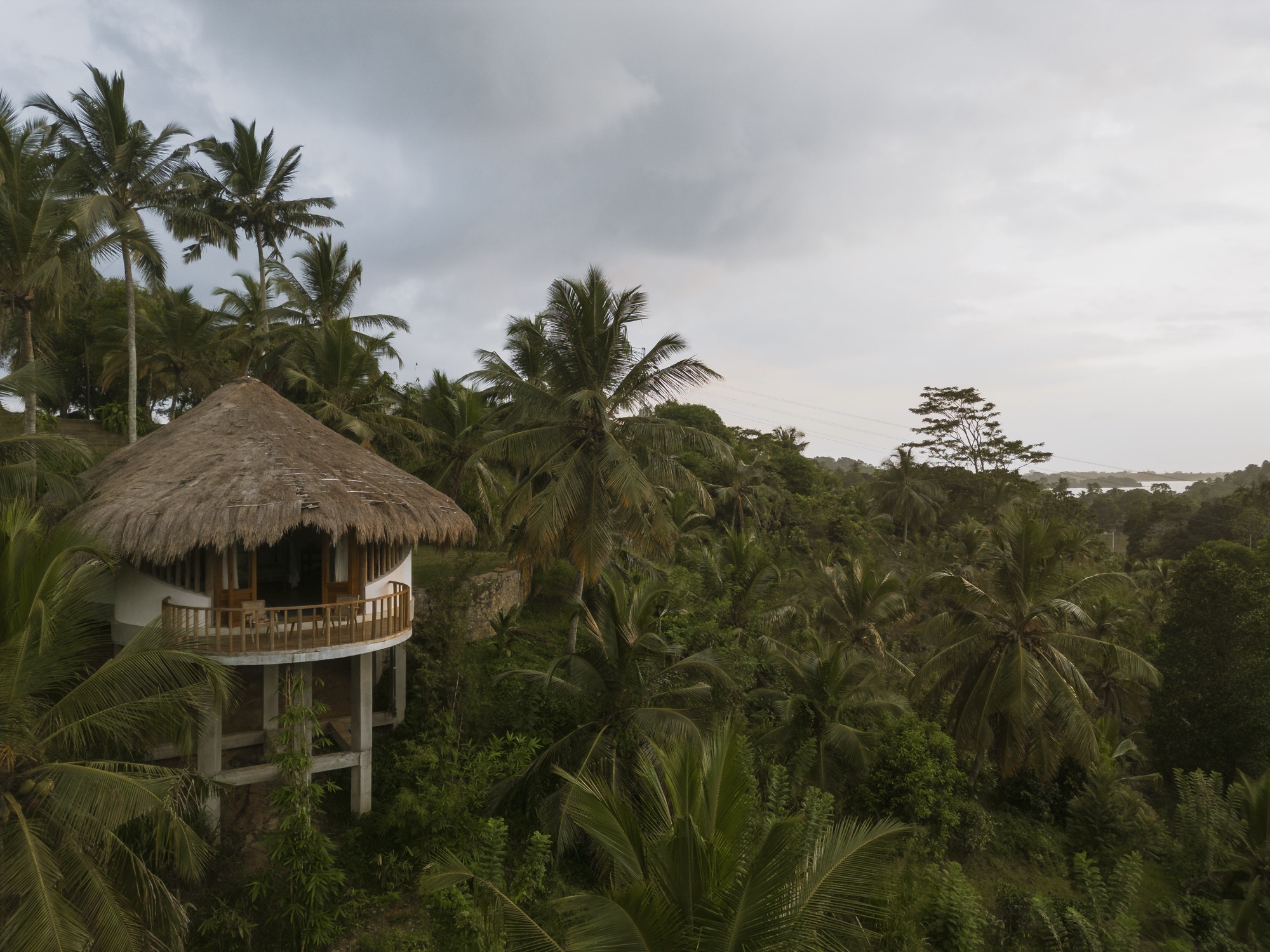 Aerial view of a round thatched cabana on stilts set in dense jungle near a lagoon — Tekanda Lodge, Ahangama
