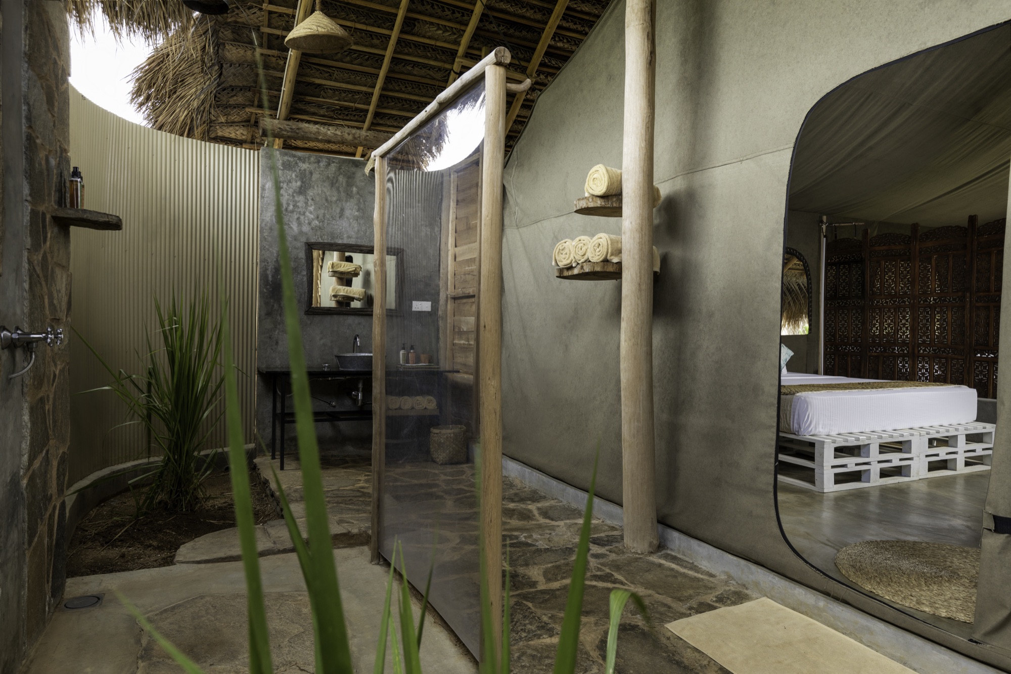 Deluxe Tent open-air bathroom with concrete sink and outdoor shower under the thatched roof
