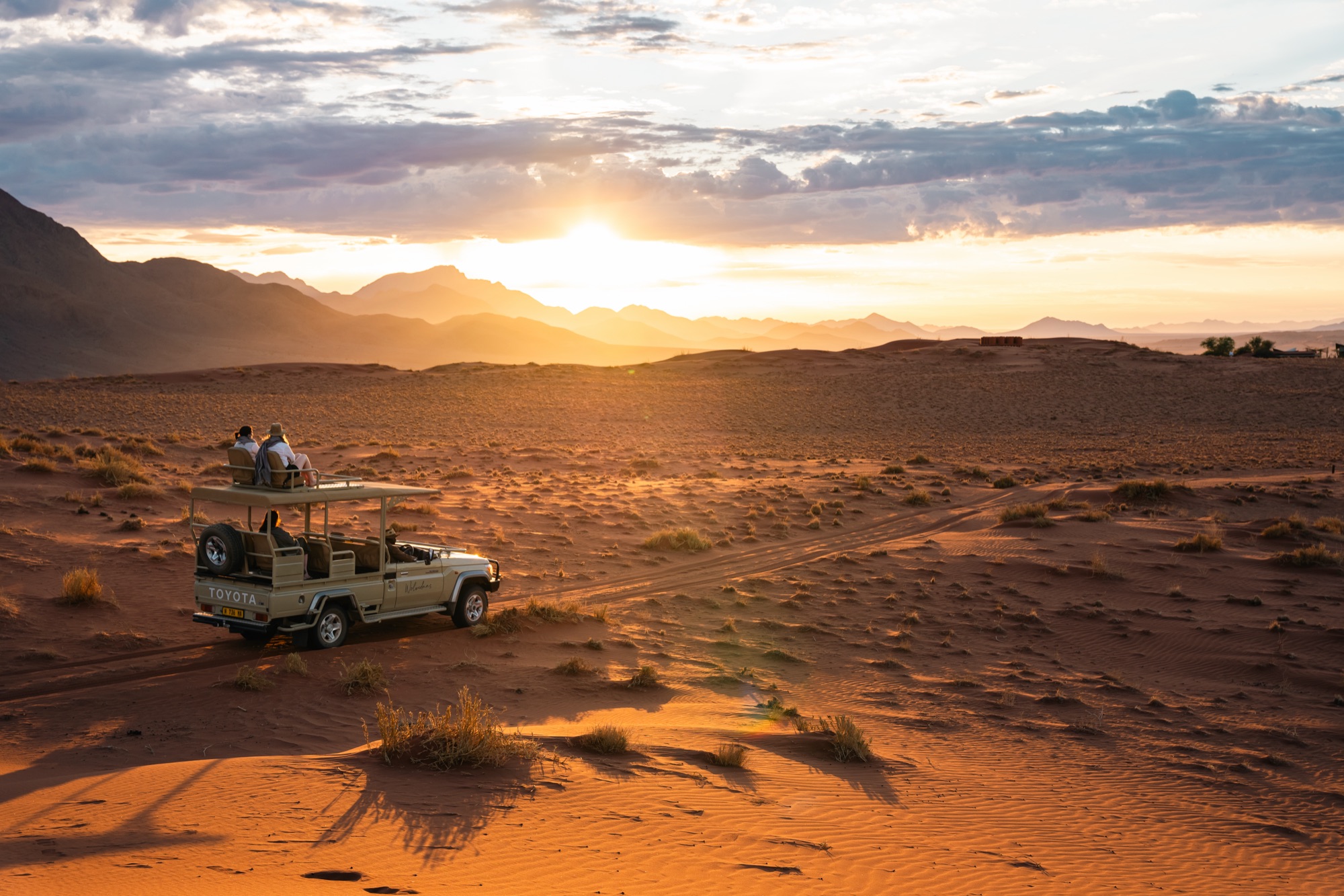 Open safari vehicle on the dunes at sunset