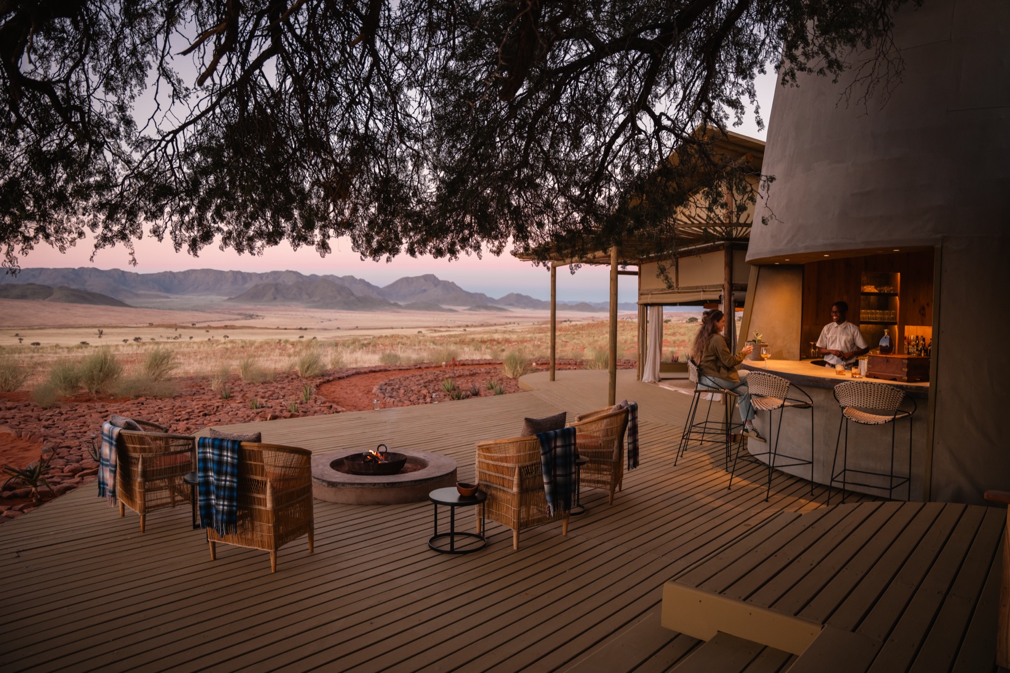 Deck with the Silo Bar and fire pit under a tree at sunset