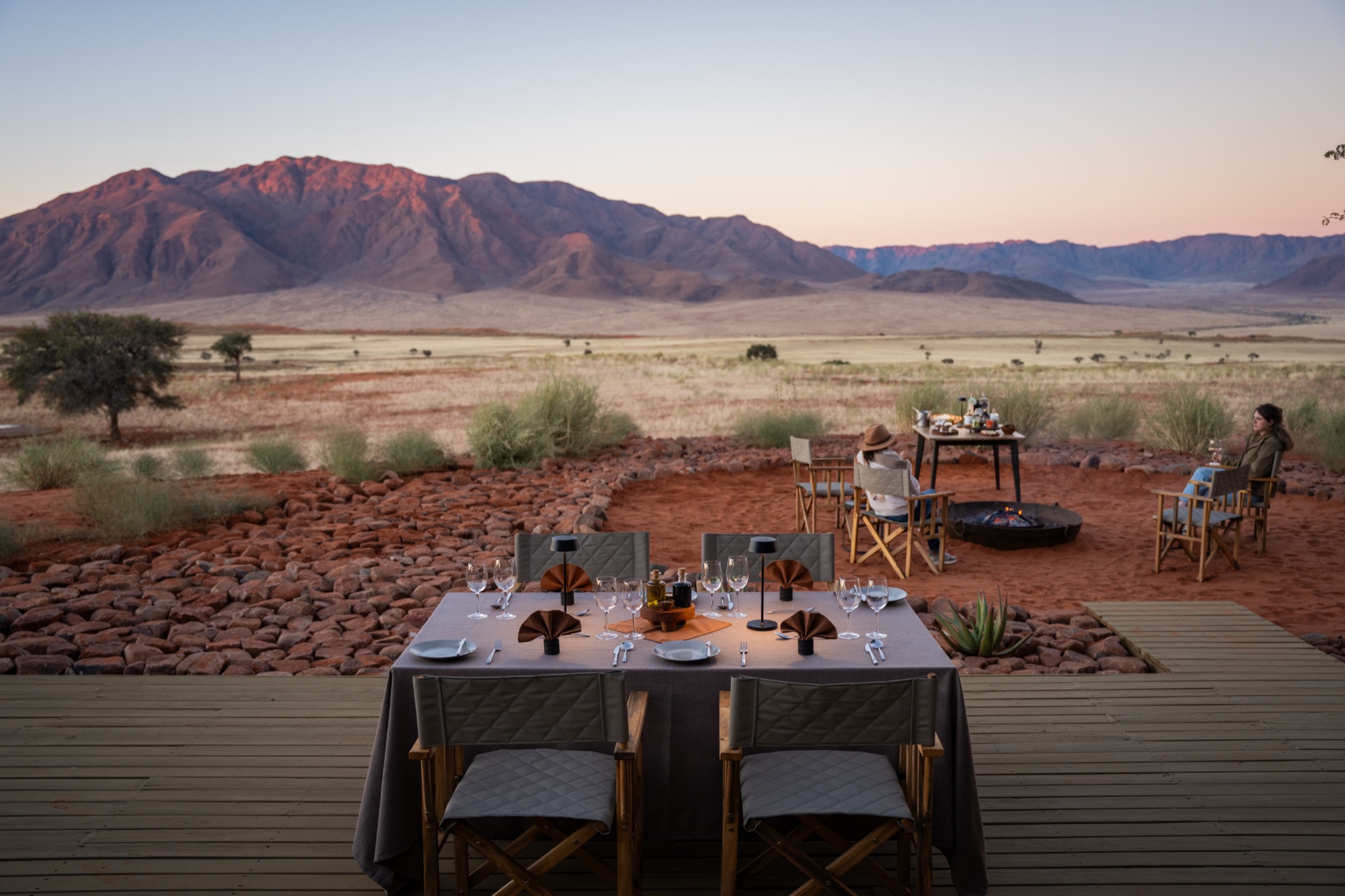 Dinner table set outdoors on the deck, mountains glowing at dusk