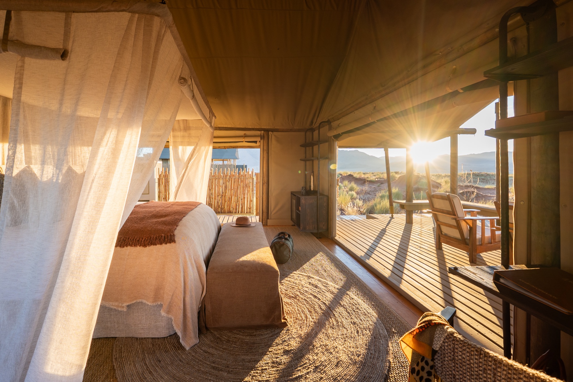 Bed under a mosquito net, the tent sides open to the sunrise