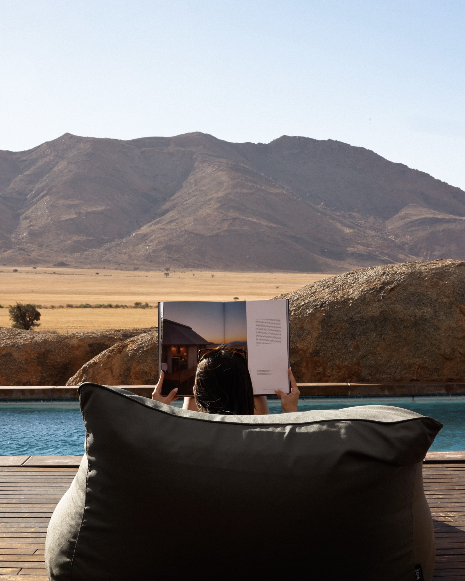 A guest on a beanbag by the pool, facing the mountains