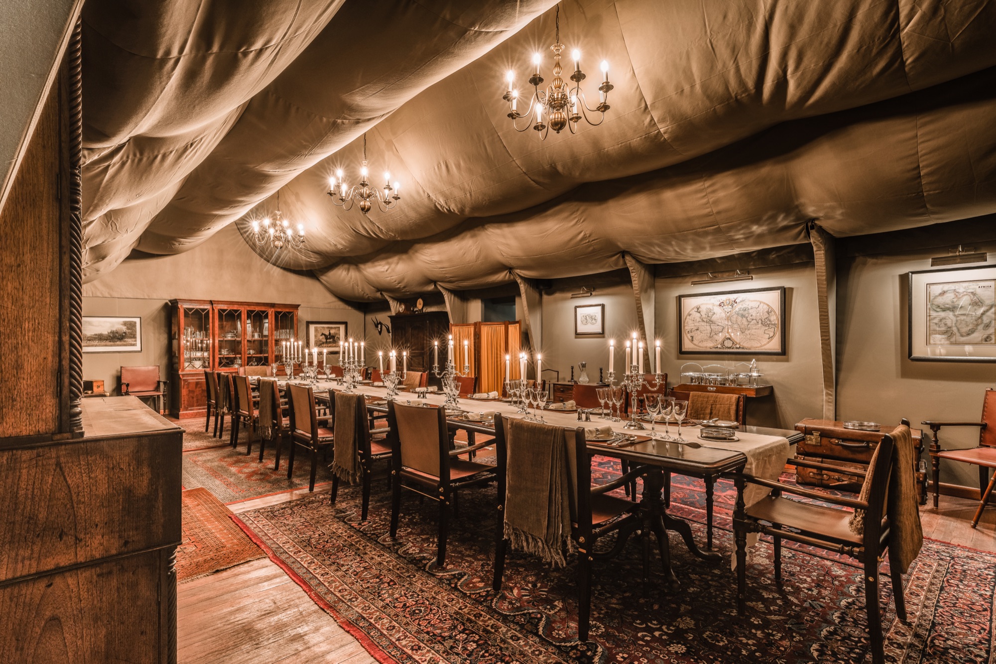 The long table of the dining tent, under candlelit chandeliers