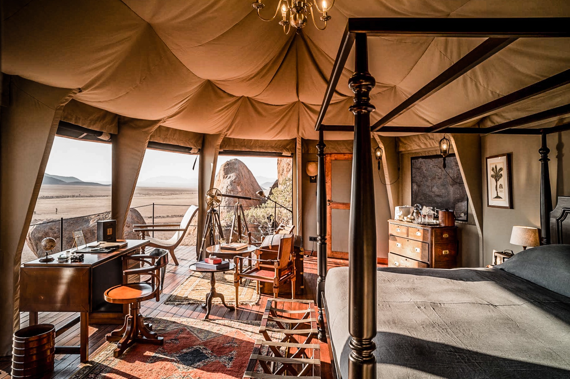Four-poster bed, desk and antiques in a tent open to the desert