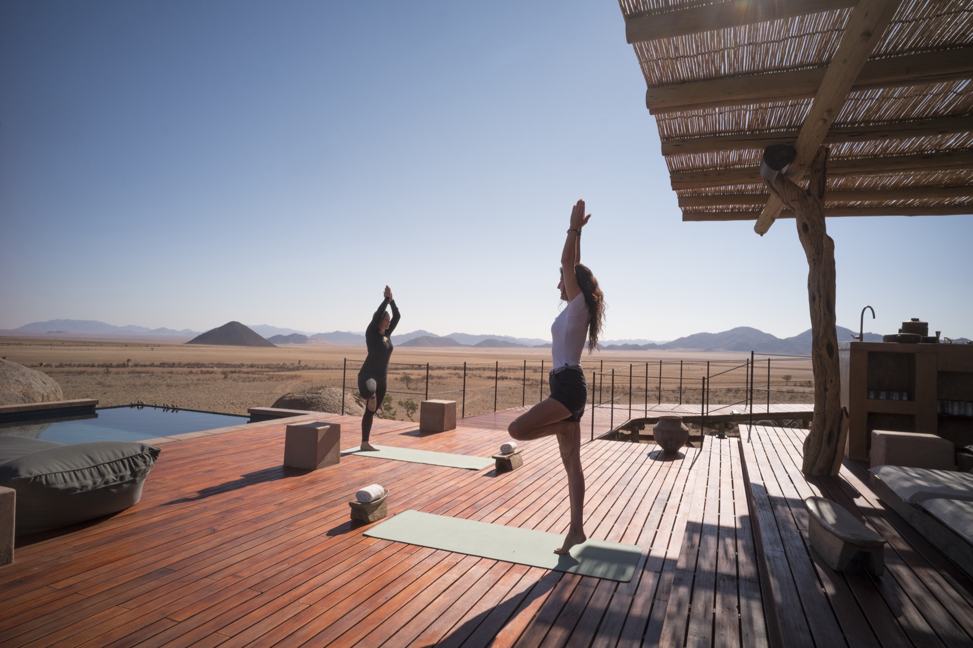 Yoga on the wooden deck by the pool, the desert behind